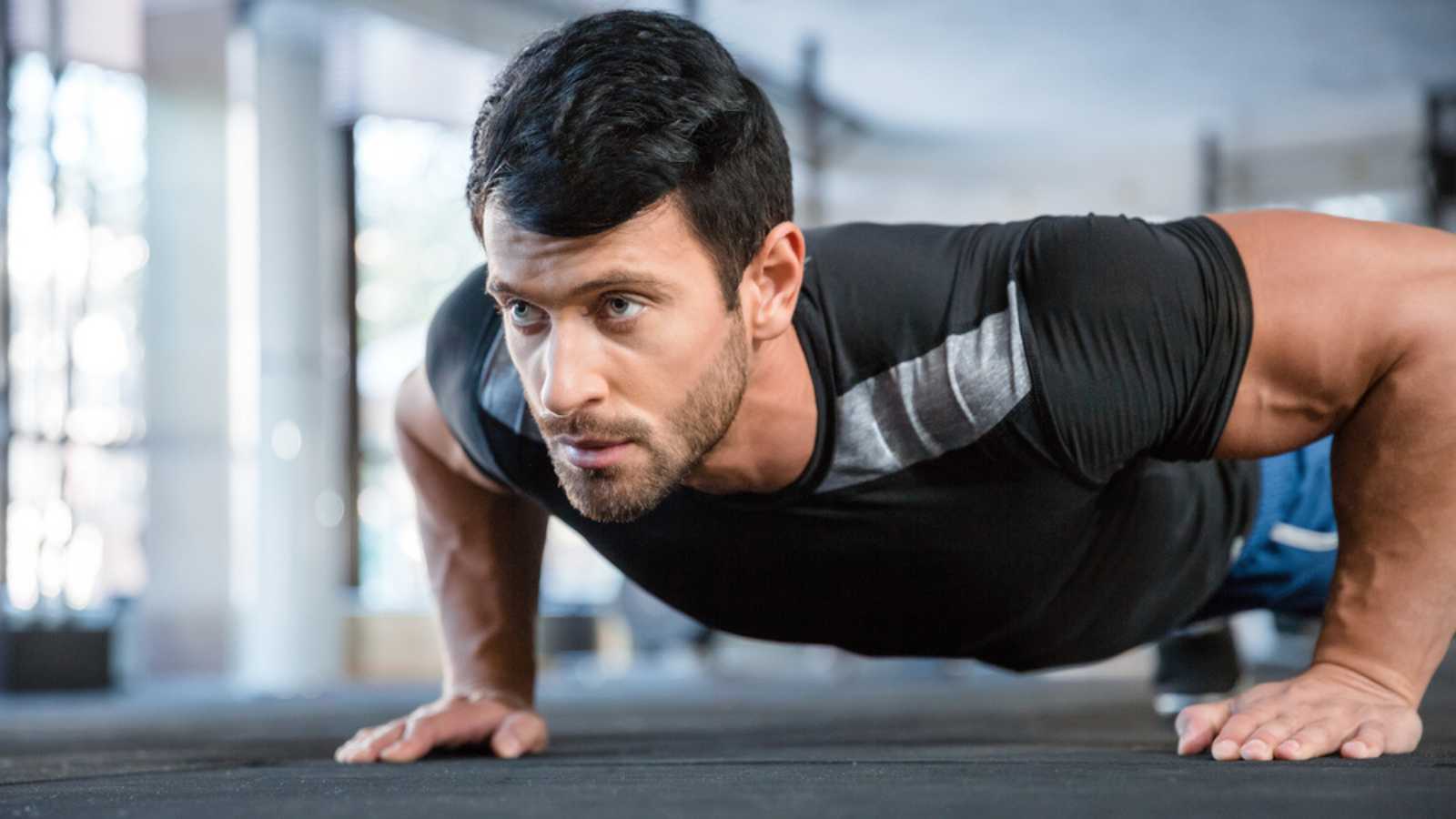 Portrait of a fitness man doing push ups in gym