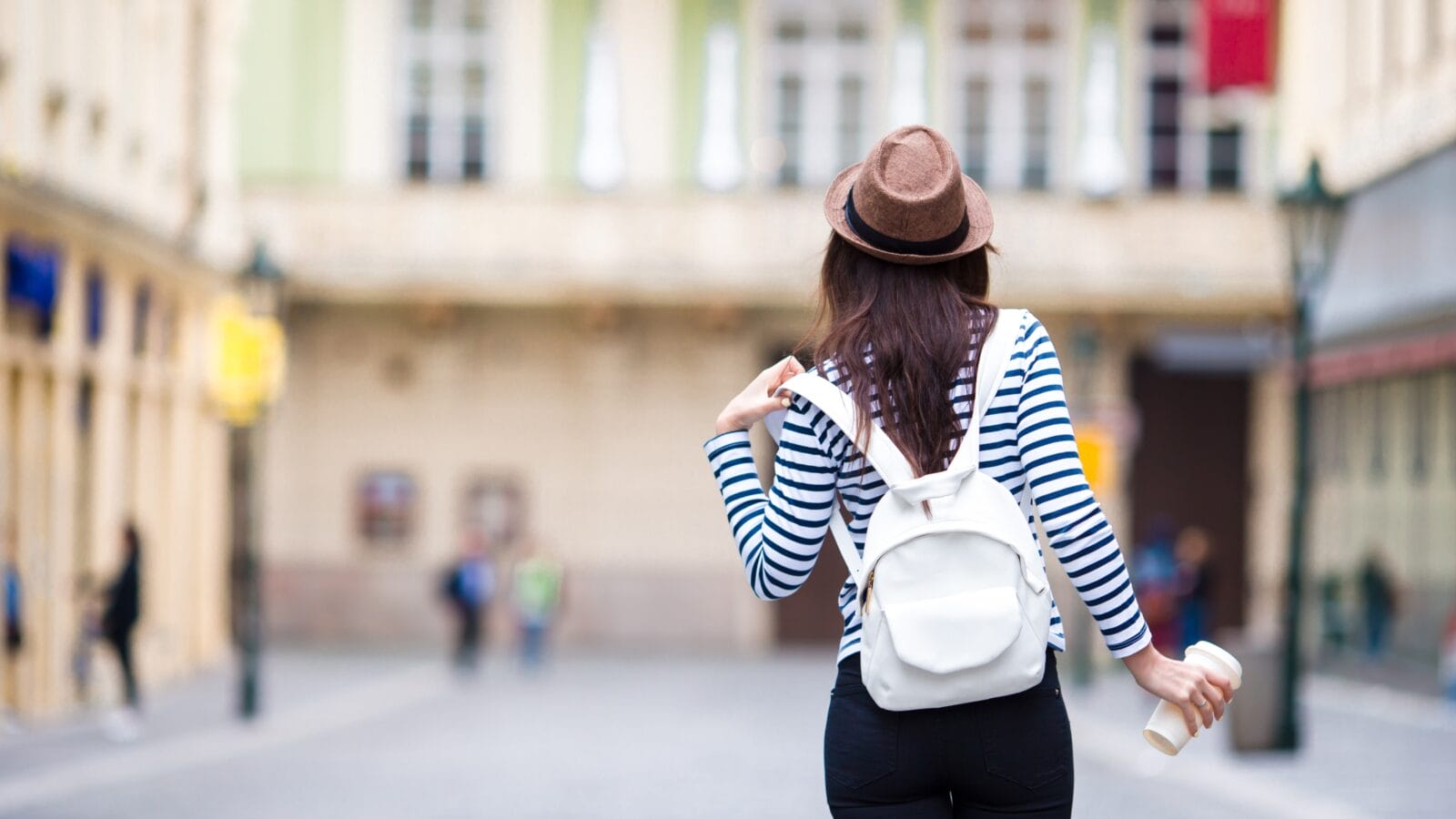 Happy young urban woman drinking coffee in european city.