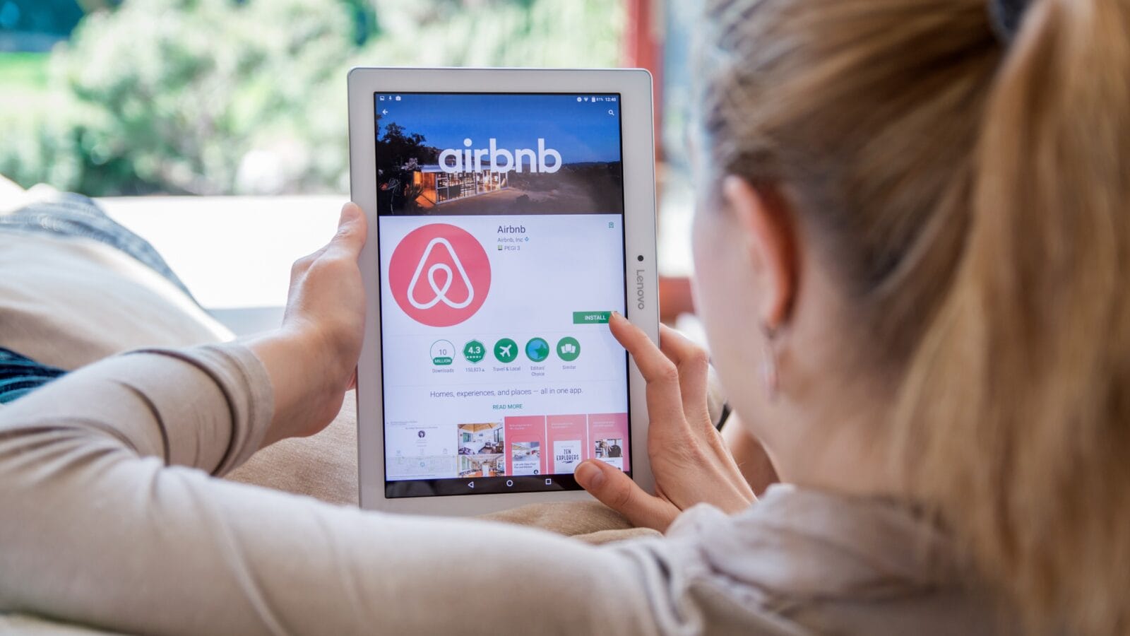 Woman with a tablet showing Airbnb app.