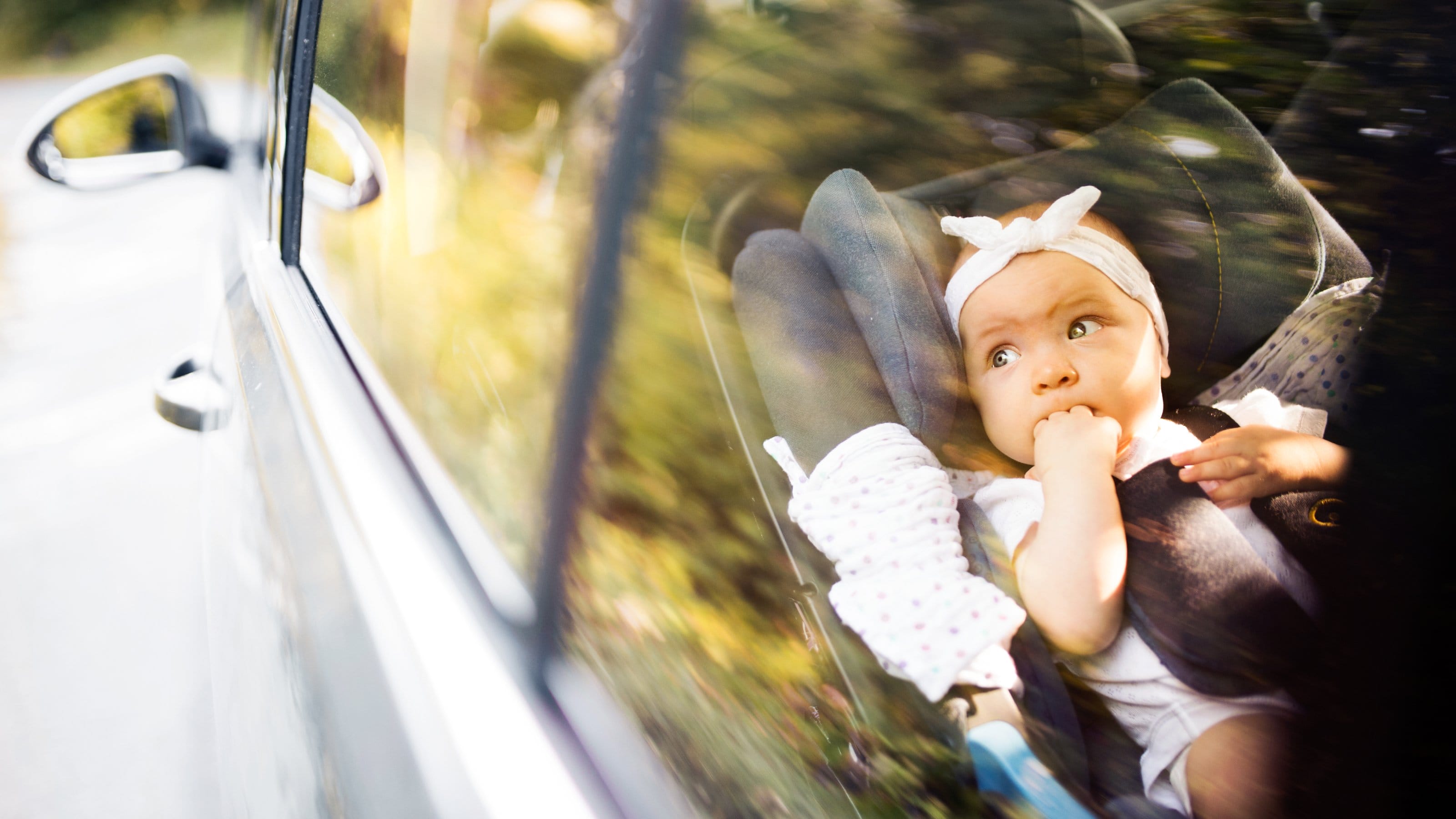 Little baby fastened with security belt in safety car seat.