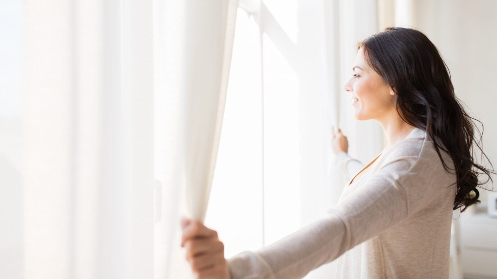 Woman opening window curtains