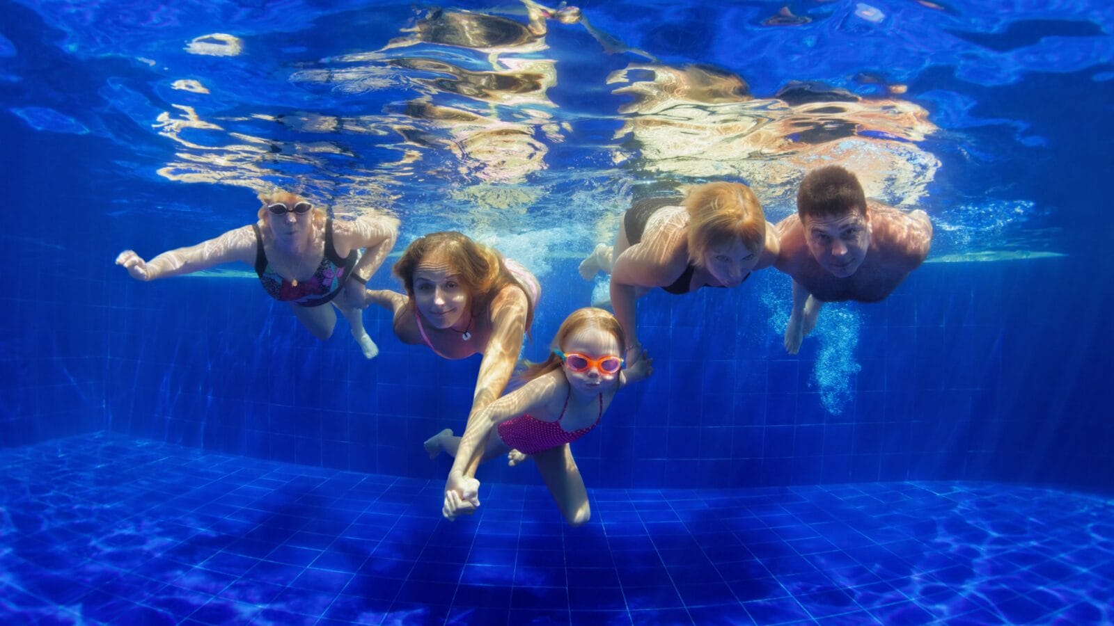 A family with grandchildren diving and having fun in a pool.