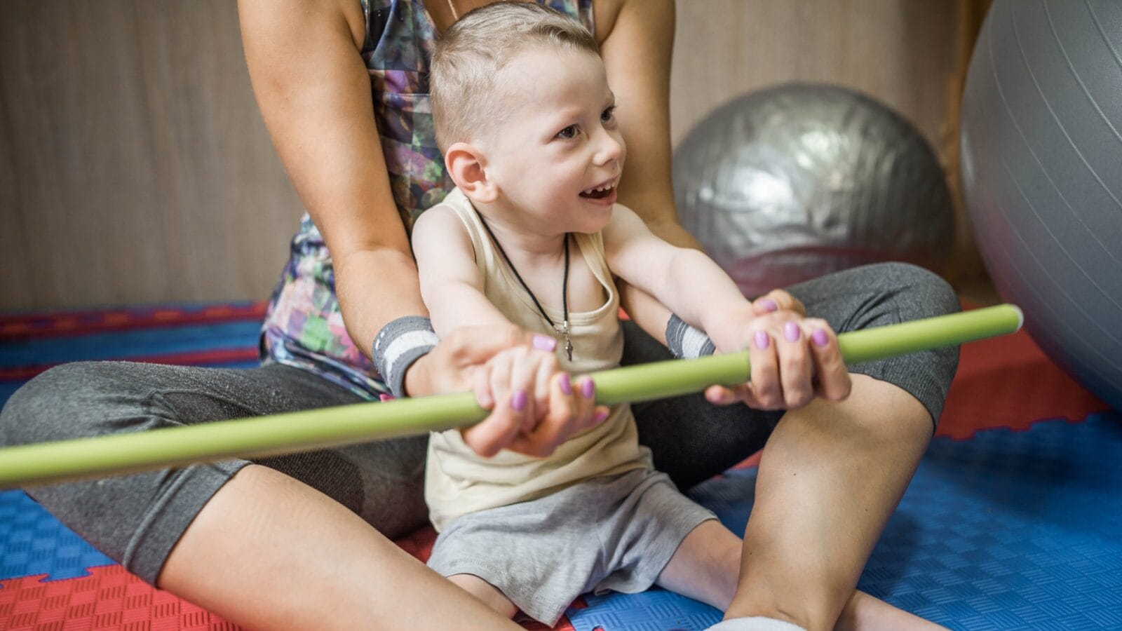little kid with cerebral palsy has musculoskeletal therapy by doing exercises in body fixing.