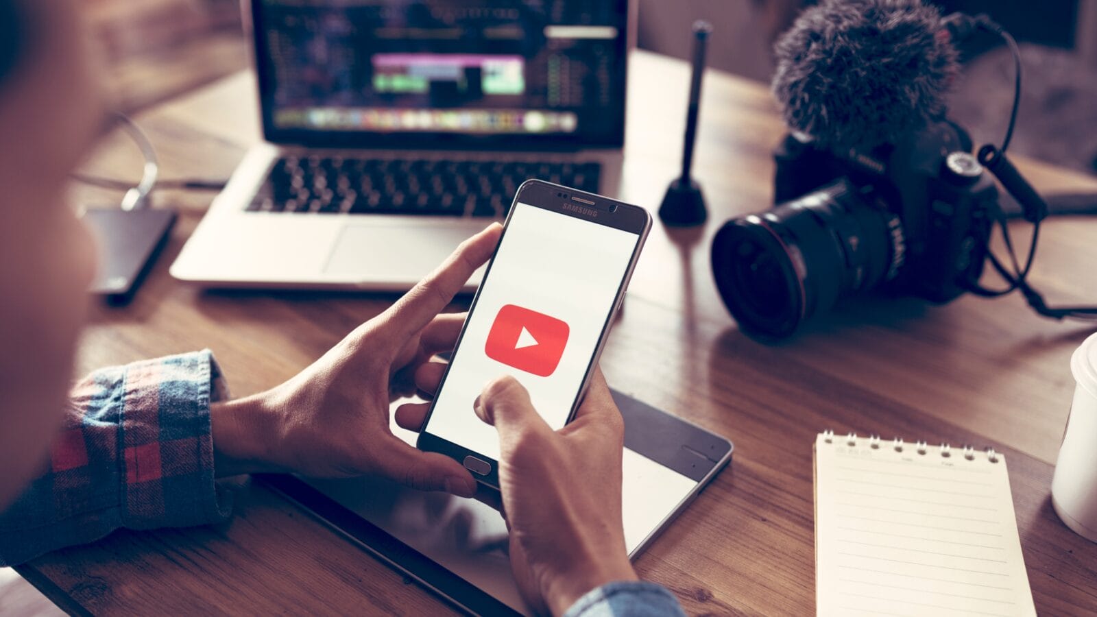 A man holding a phone with a youtube app opened.