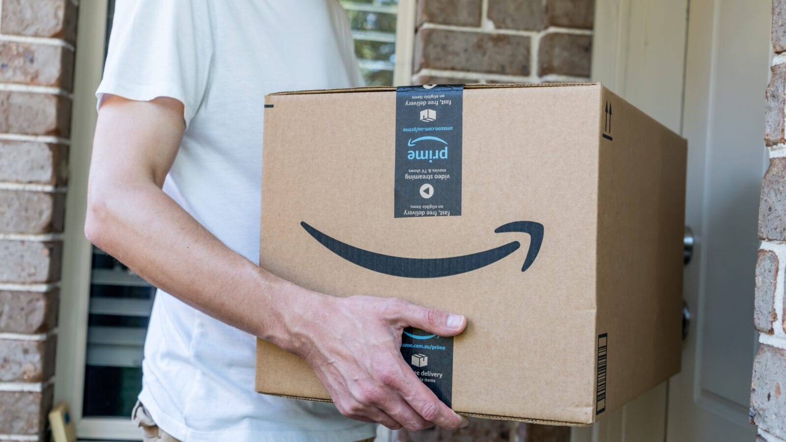 A man delivering amazon prime package to a front door.