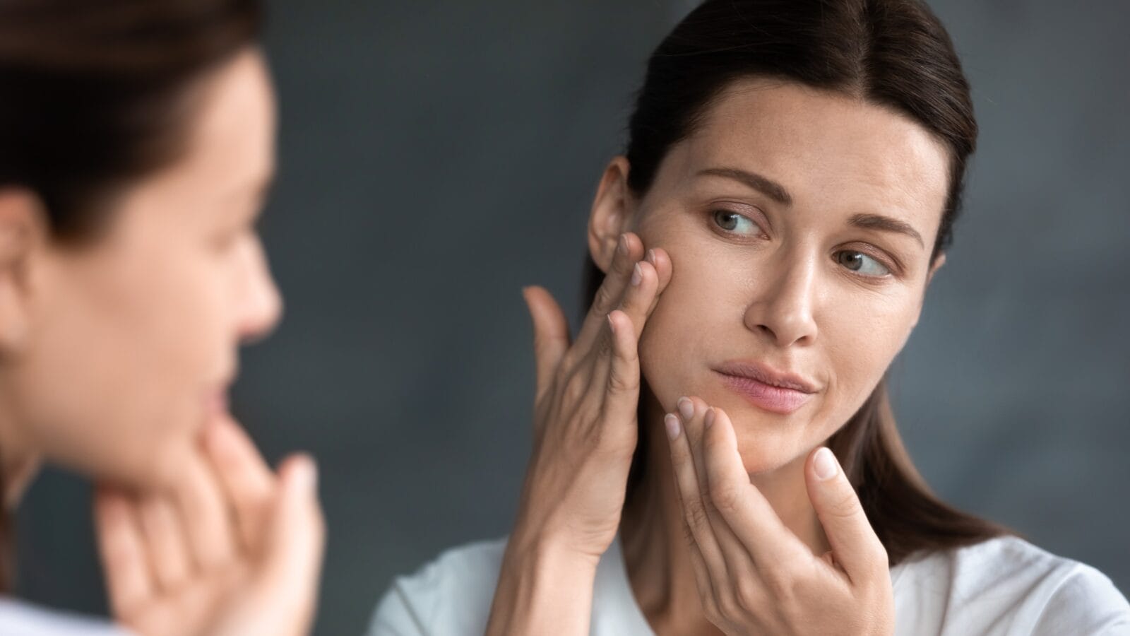 Close up of a woman looking in mirror checking dry skin.