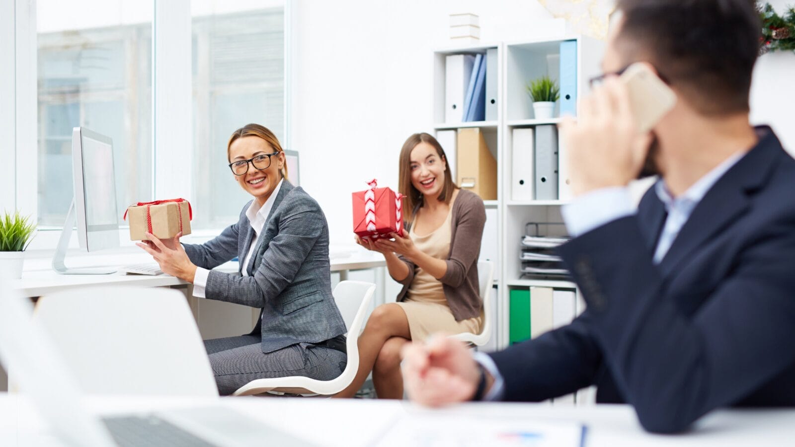 Businesswomen showing gifts to colleague.