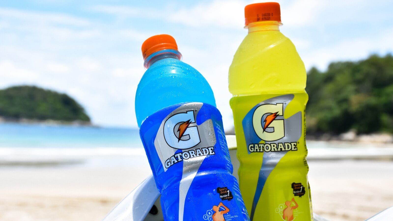 Two bottles of Gatorade closeup on a beach.
