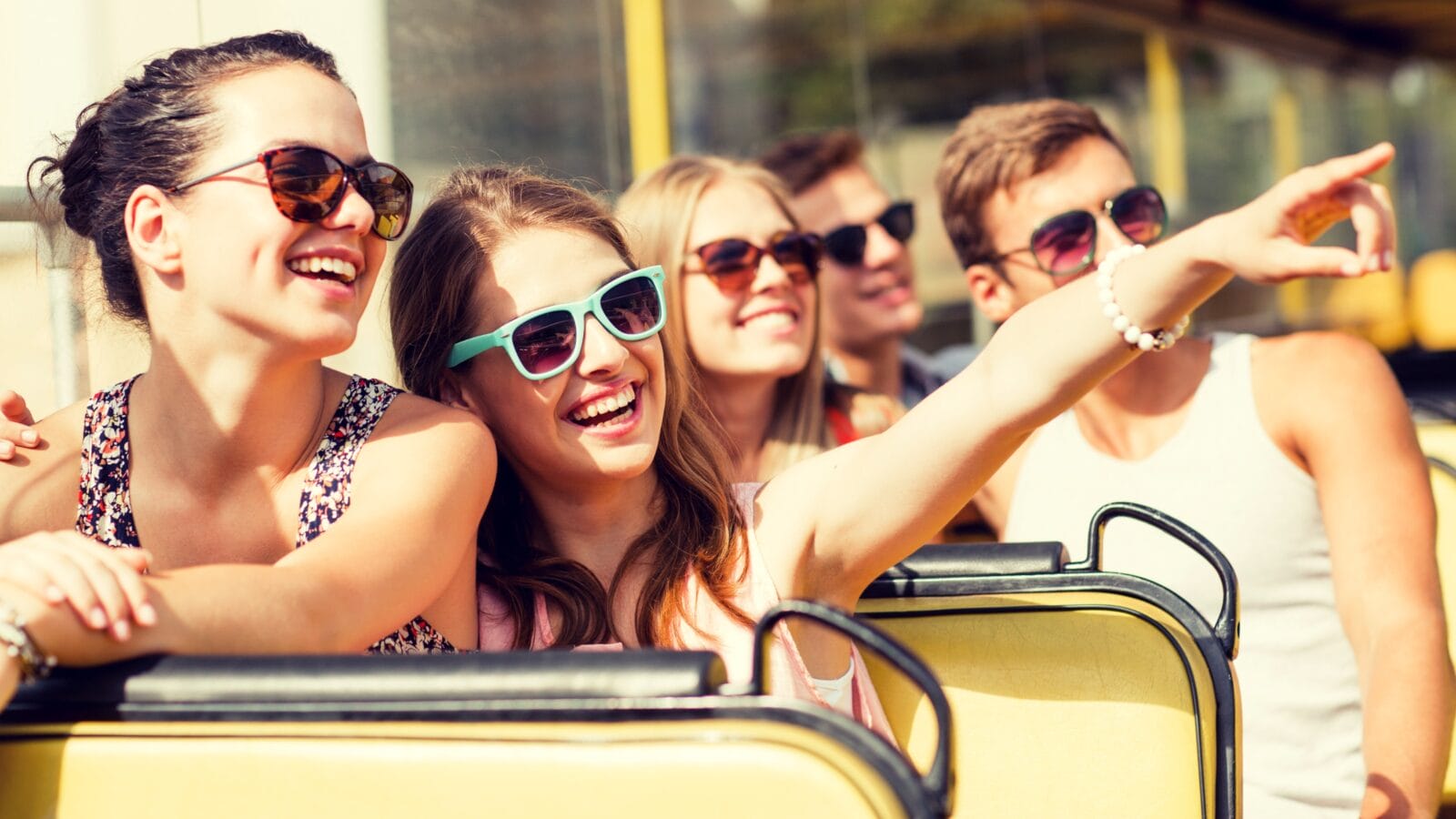 group of smiling friends traveling by tour bus