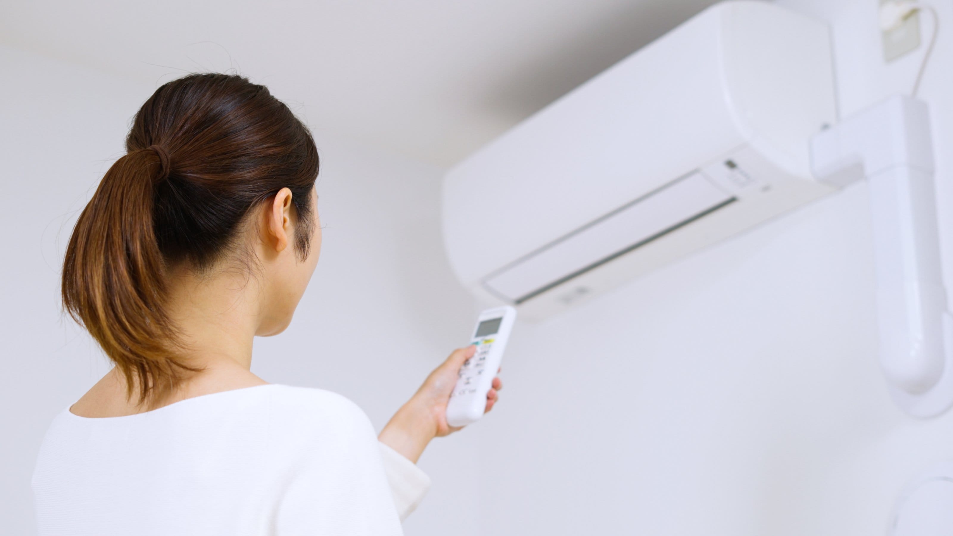 A woman turning off an air conditioner.