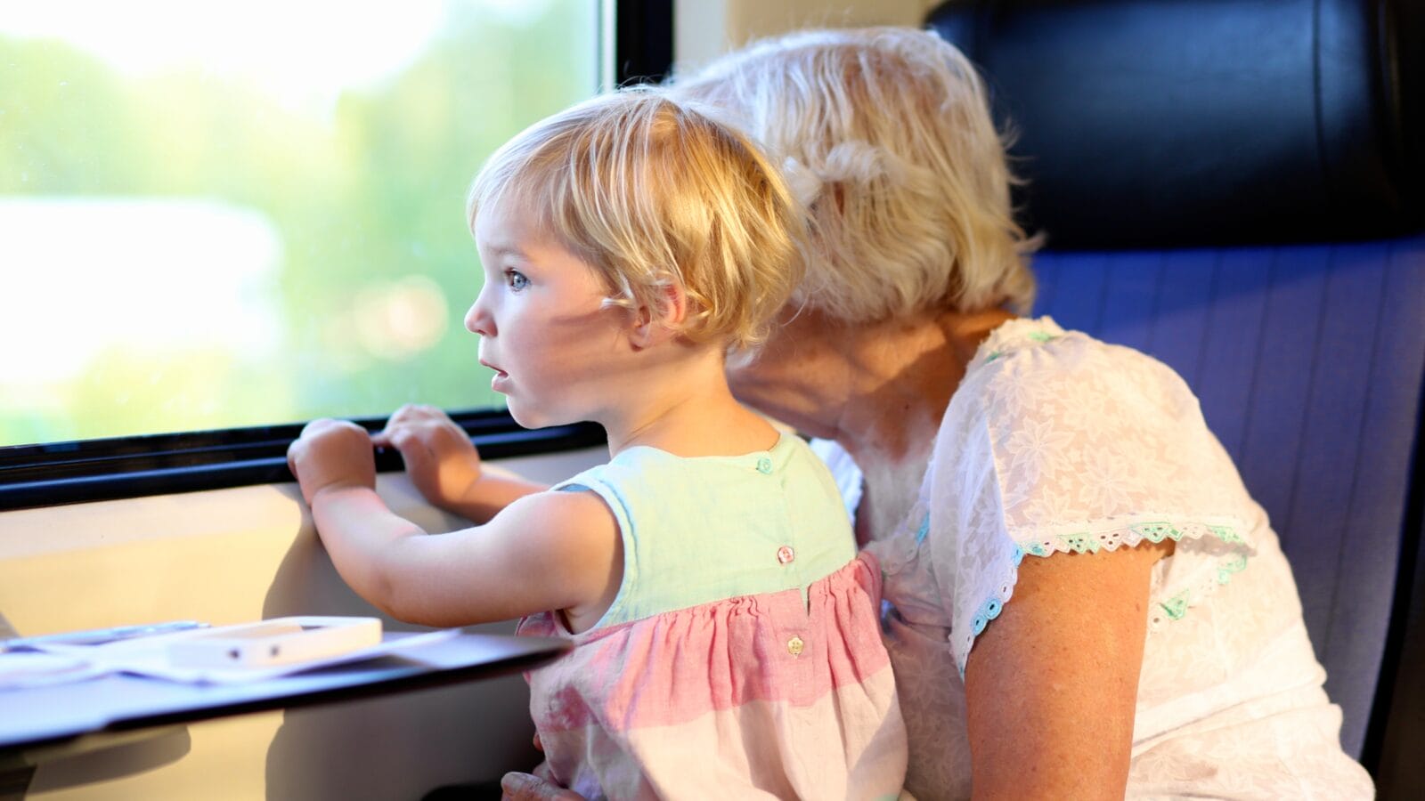 Grandmother with granddaughter traveling together by train.