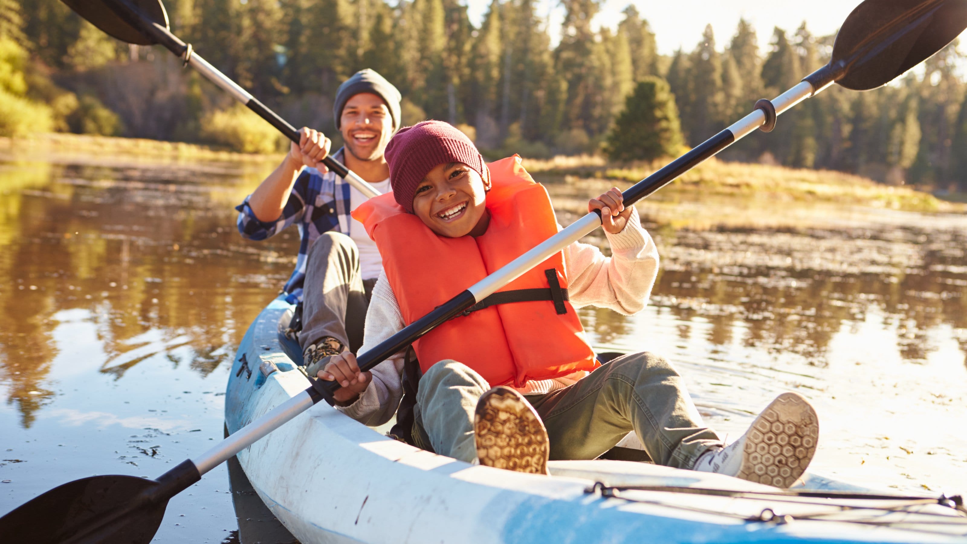 Father And Son Rowing Kayak On Lake