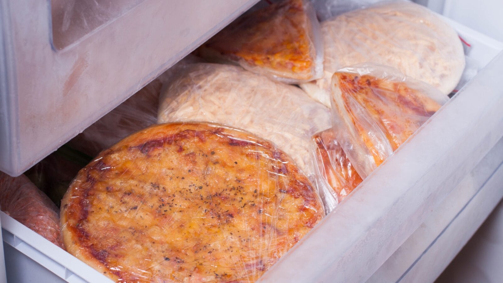 Frozen pizzas in a fridge.