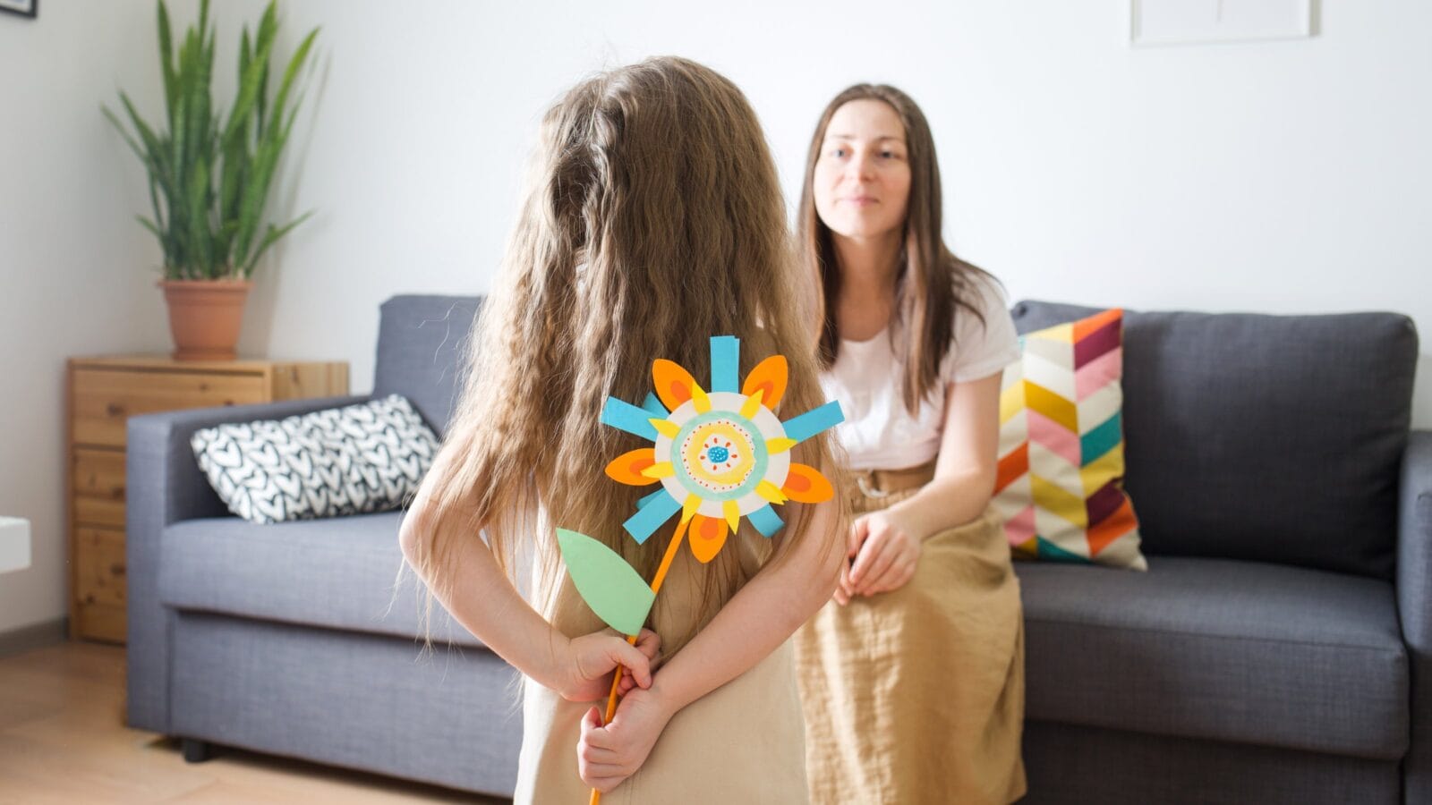 Child gives her mom flower made of paper.