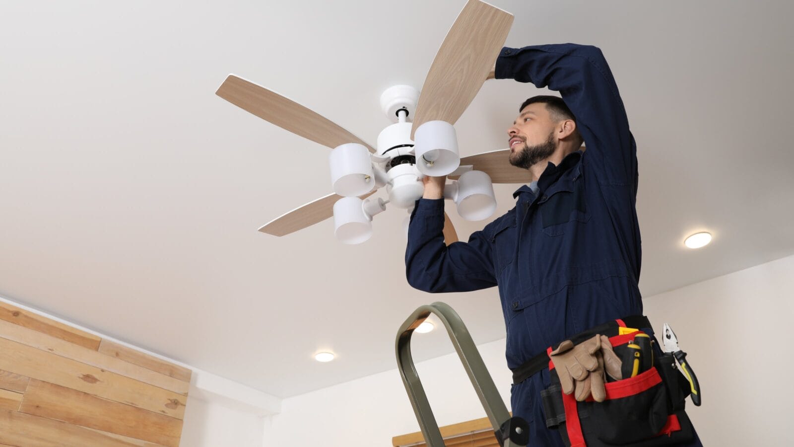 A man installing ceiling fan at home.