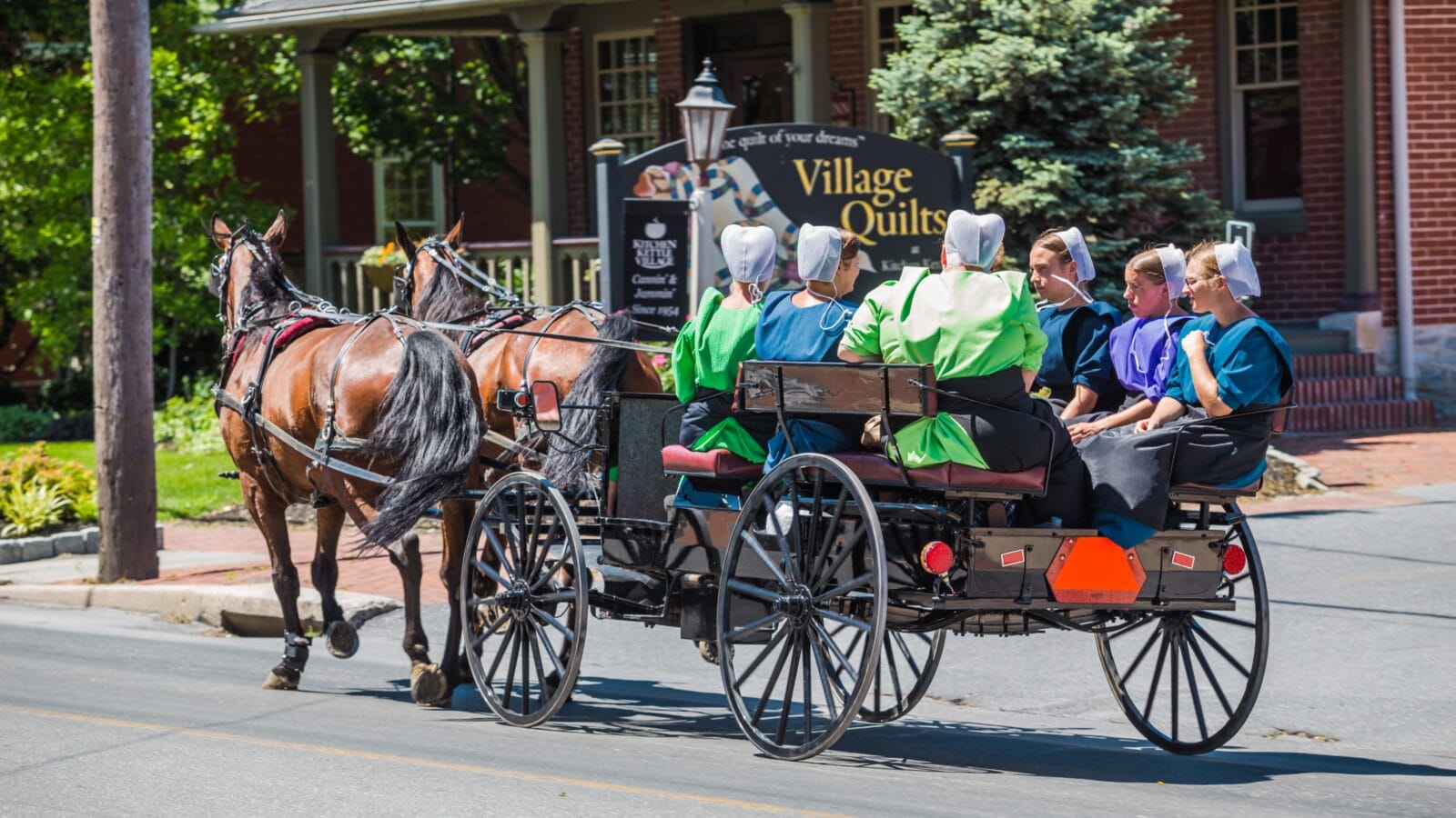 An Amish wagon pulled by two horses on a village road in Lancaster County