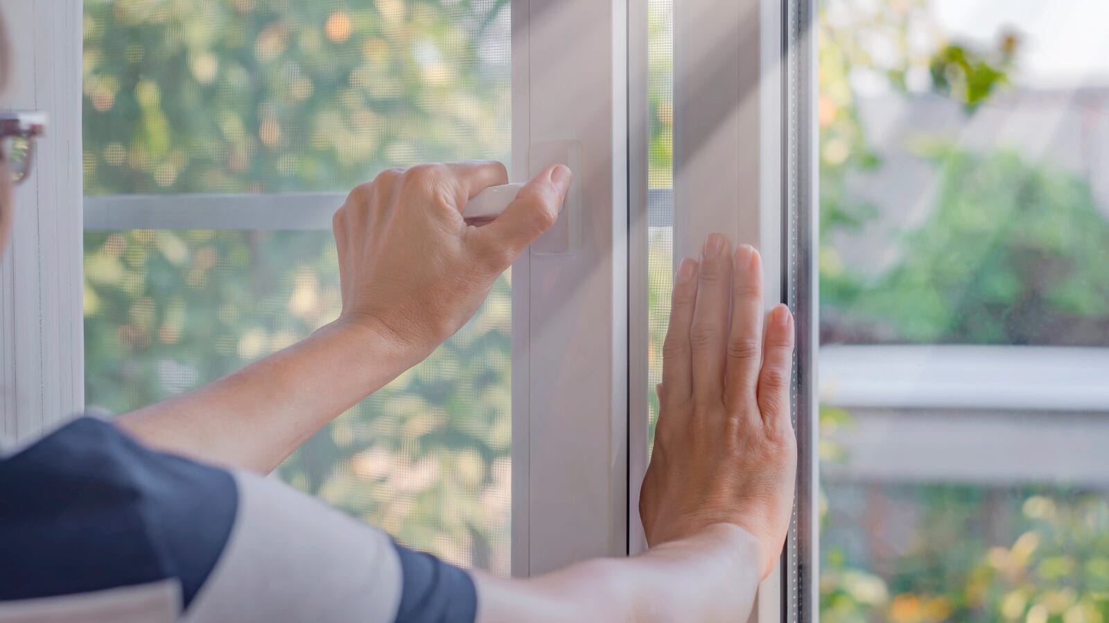 a woman closes a window in a room