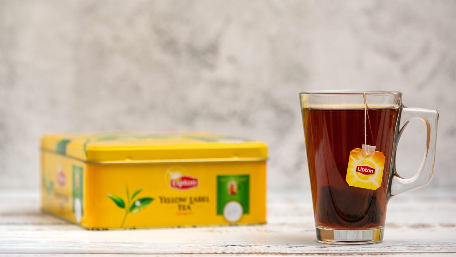 Lipton tea in cup and tea bags and box on light background.