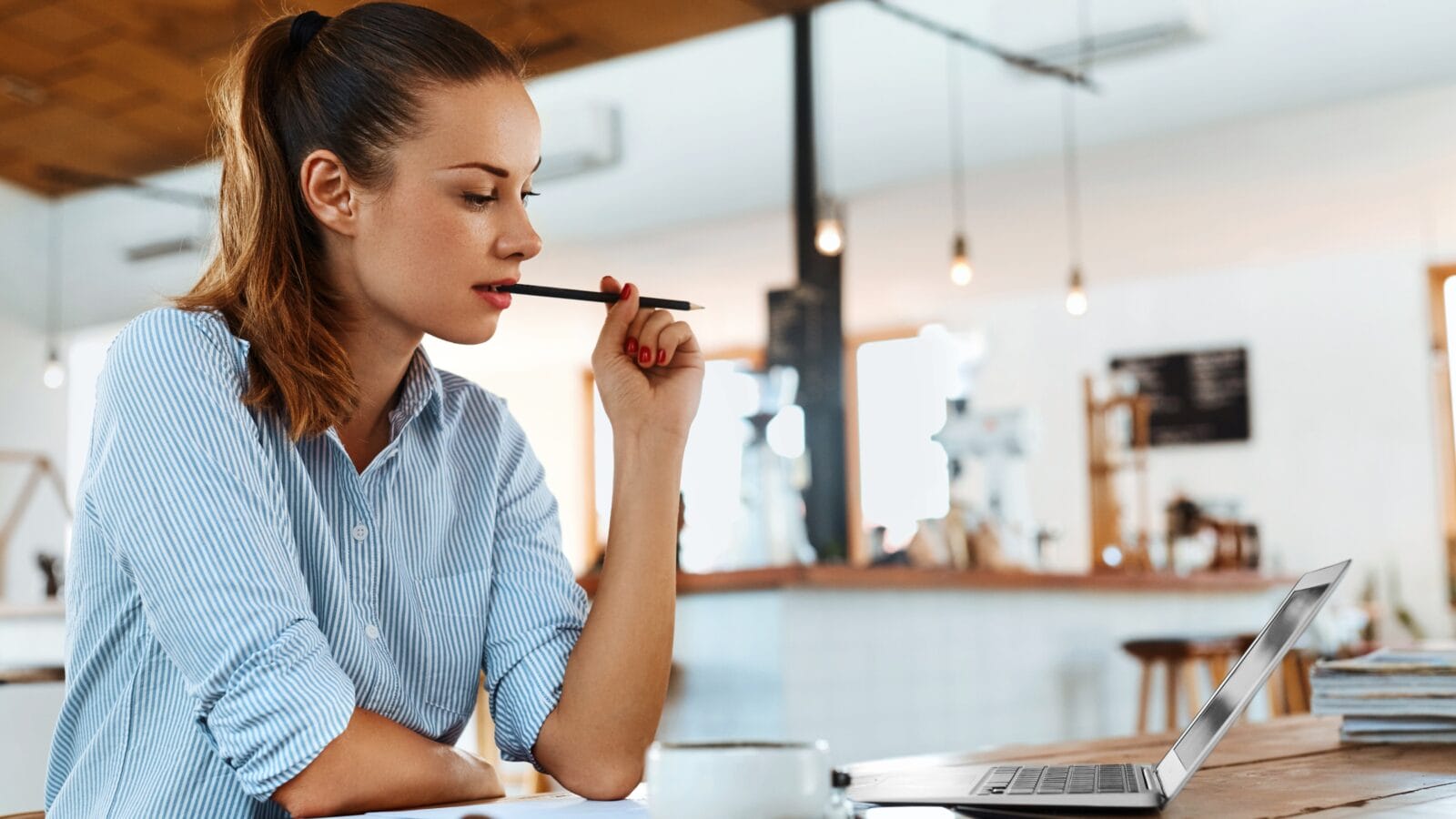 Young freelancer woman sitting on a table using a lap top.