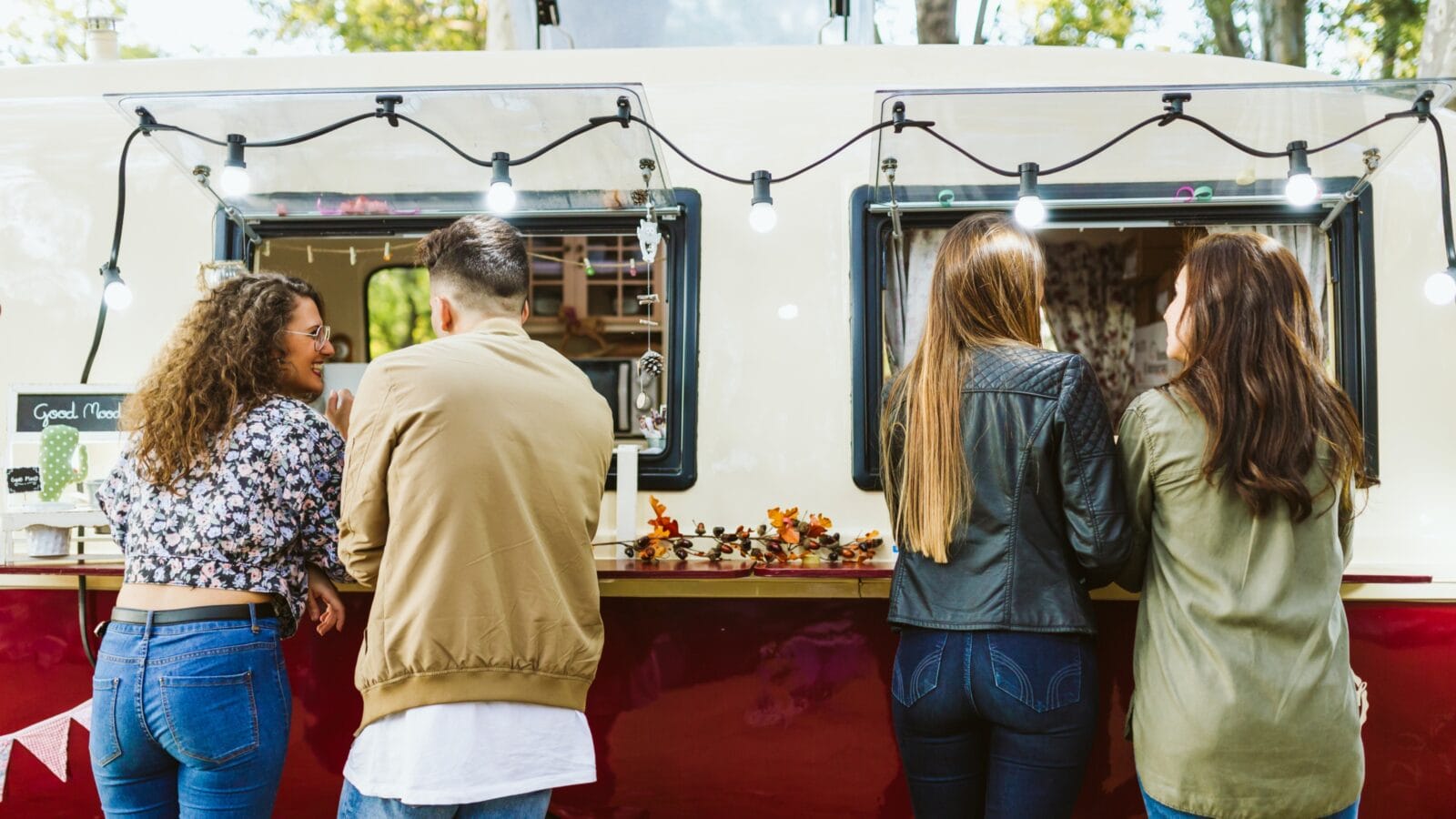 Portrait of group of friends staying in front of a food truck.