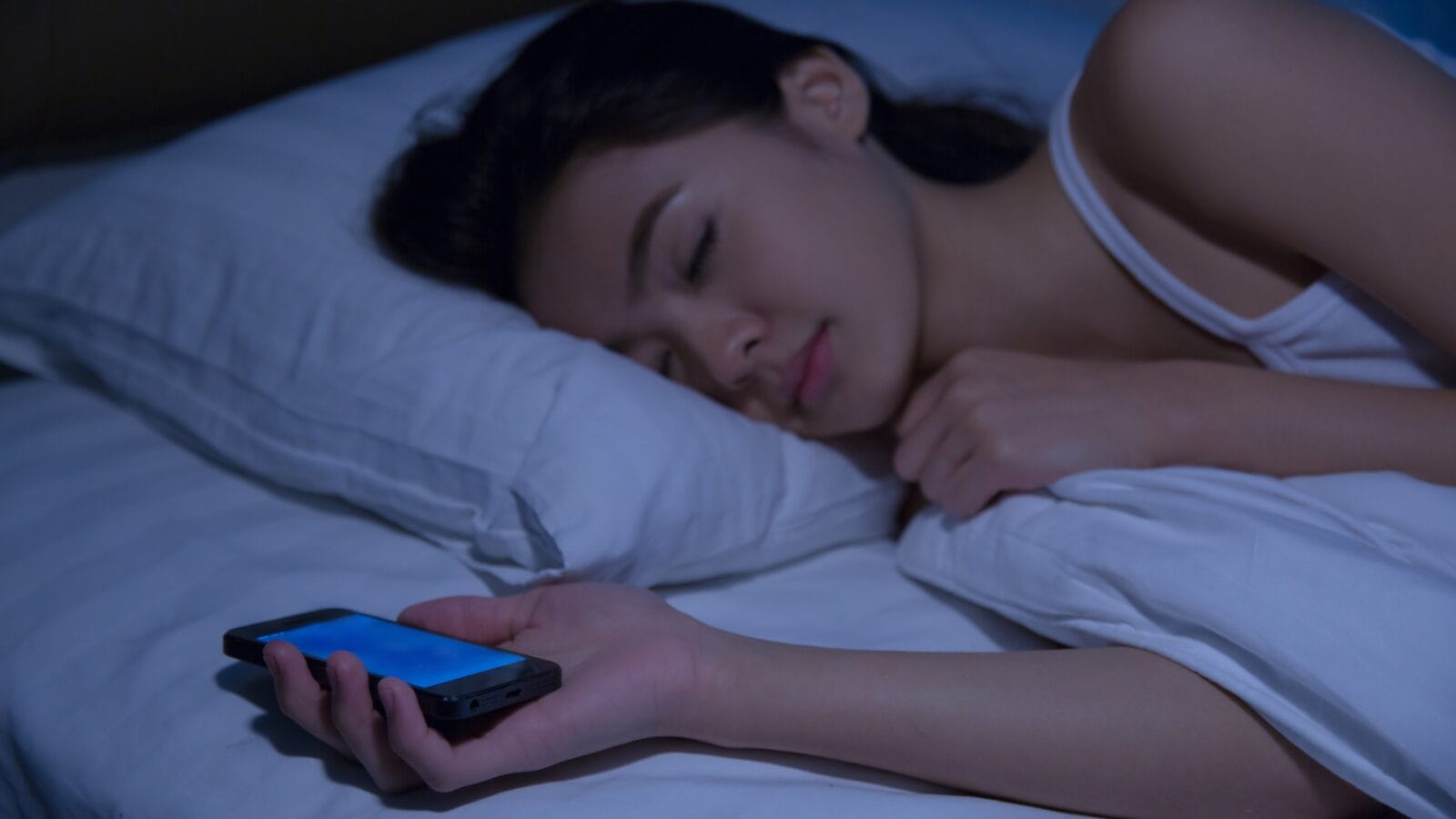 A woman asleep with a phone in hand.
