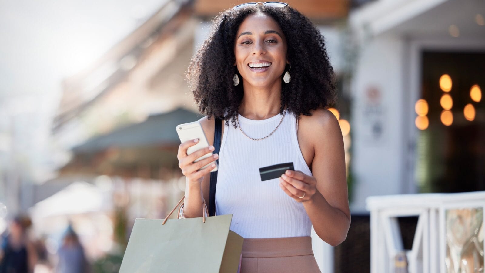 A girl with a card, mobile and shopping bag.