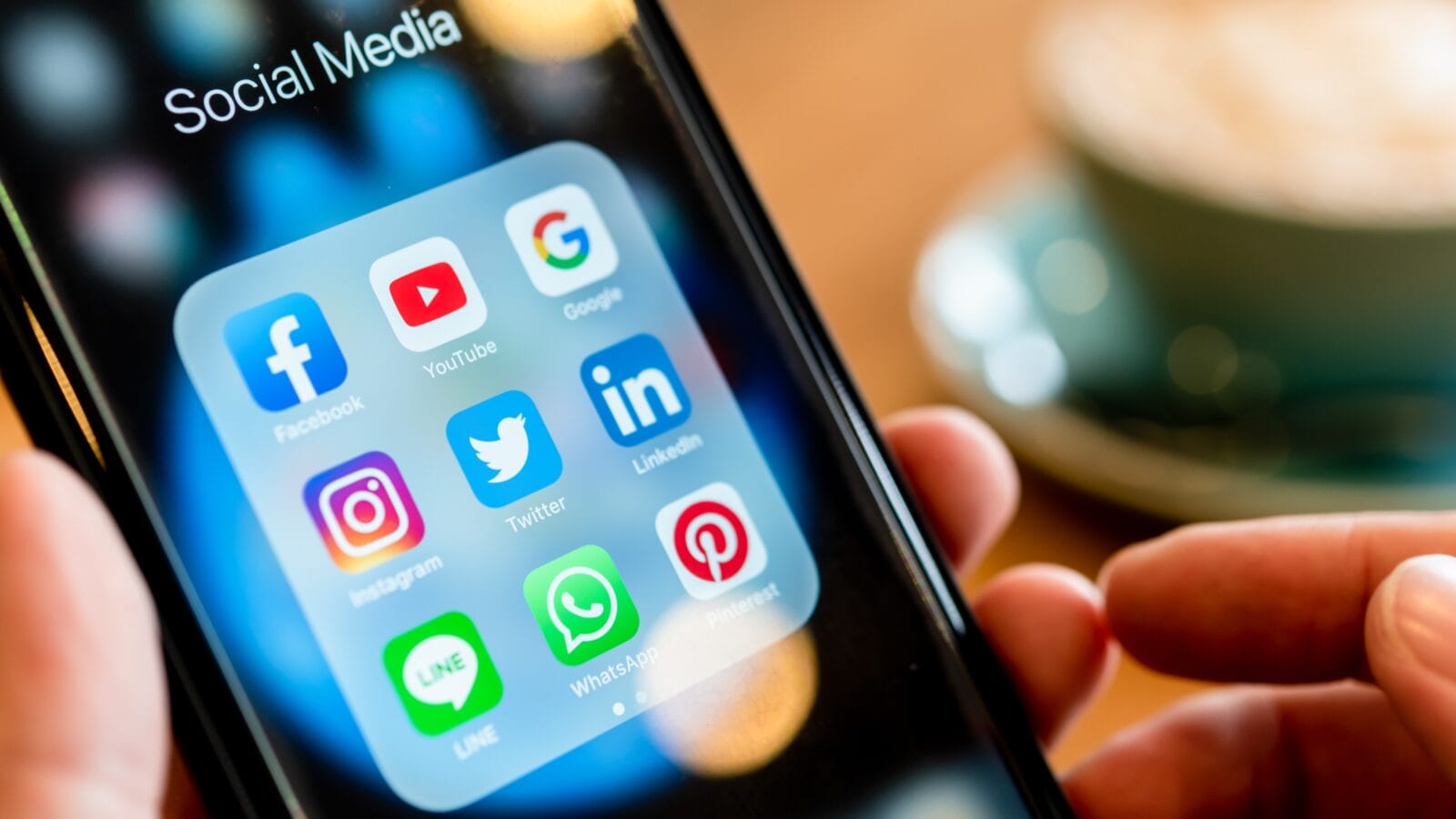 A man holding phone with social media apps.