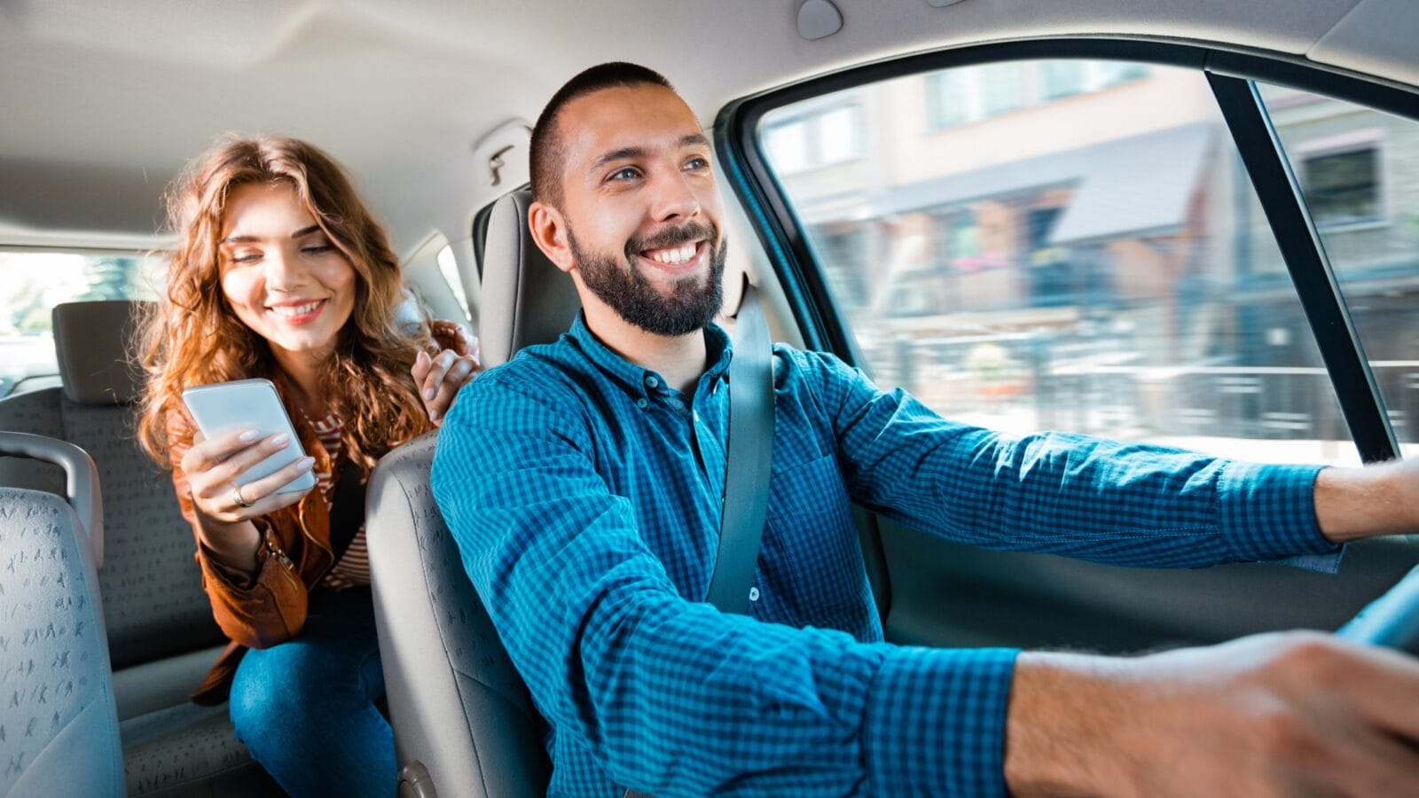 Smiling driver talking with female passenger.