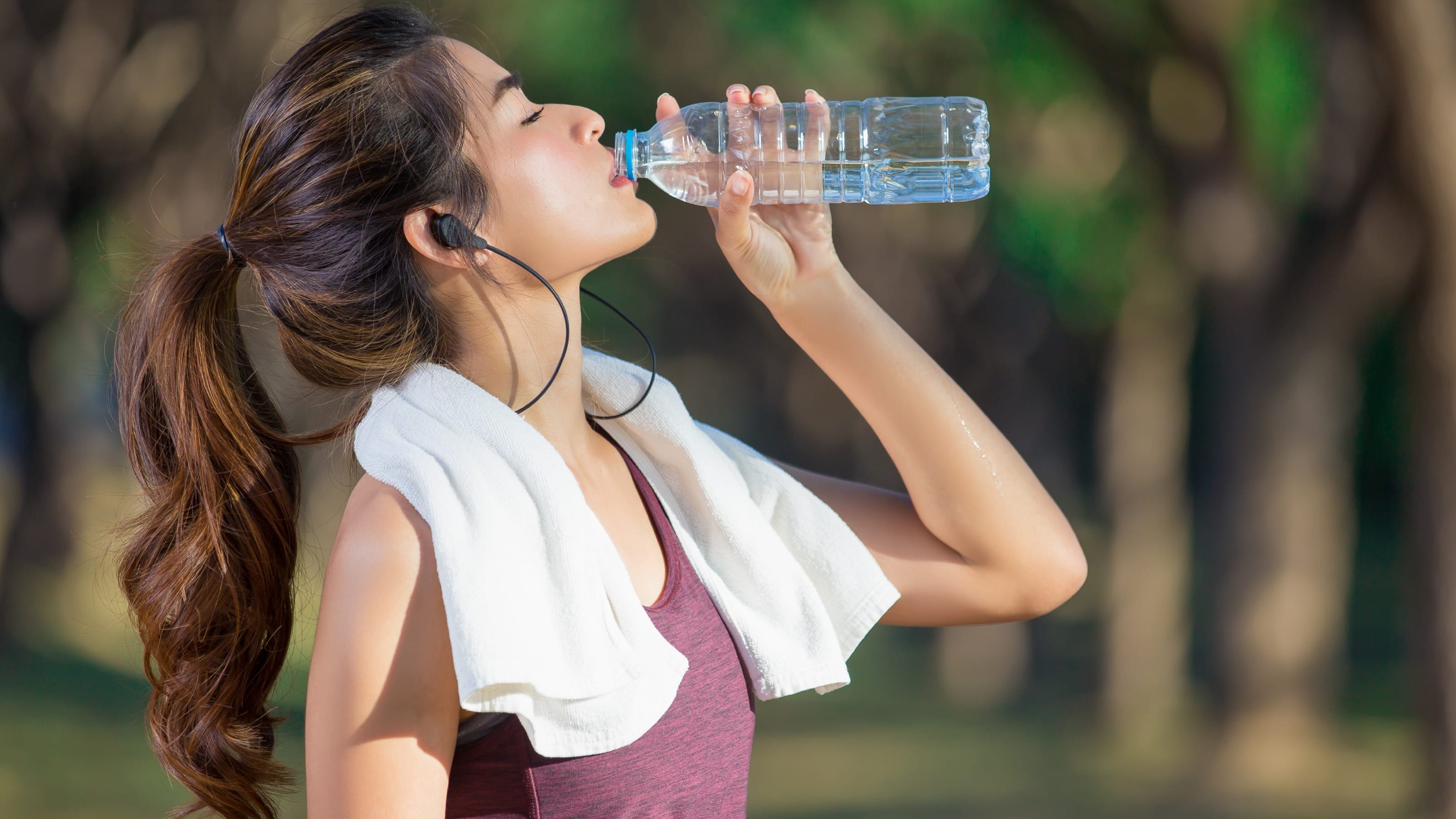 Young woman drinking water after jogging.