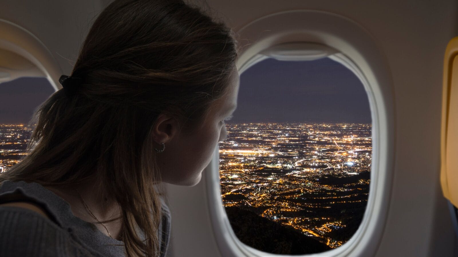 Woman looking out of the plane from the window during a night flight.