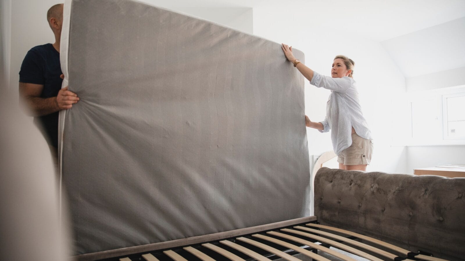 Mature couple are setting up their bed with new mattress.