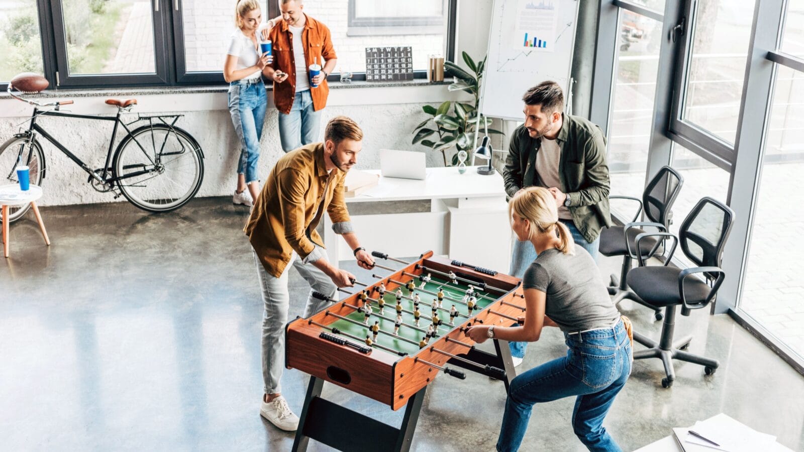 high angle view of young casual business people playing table football at office and having fun together