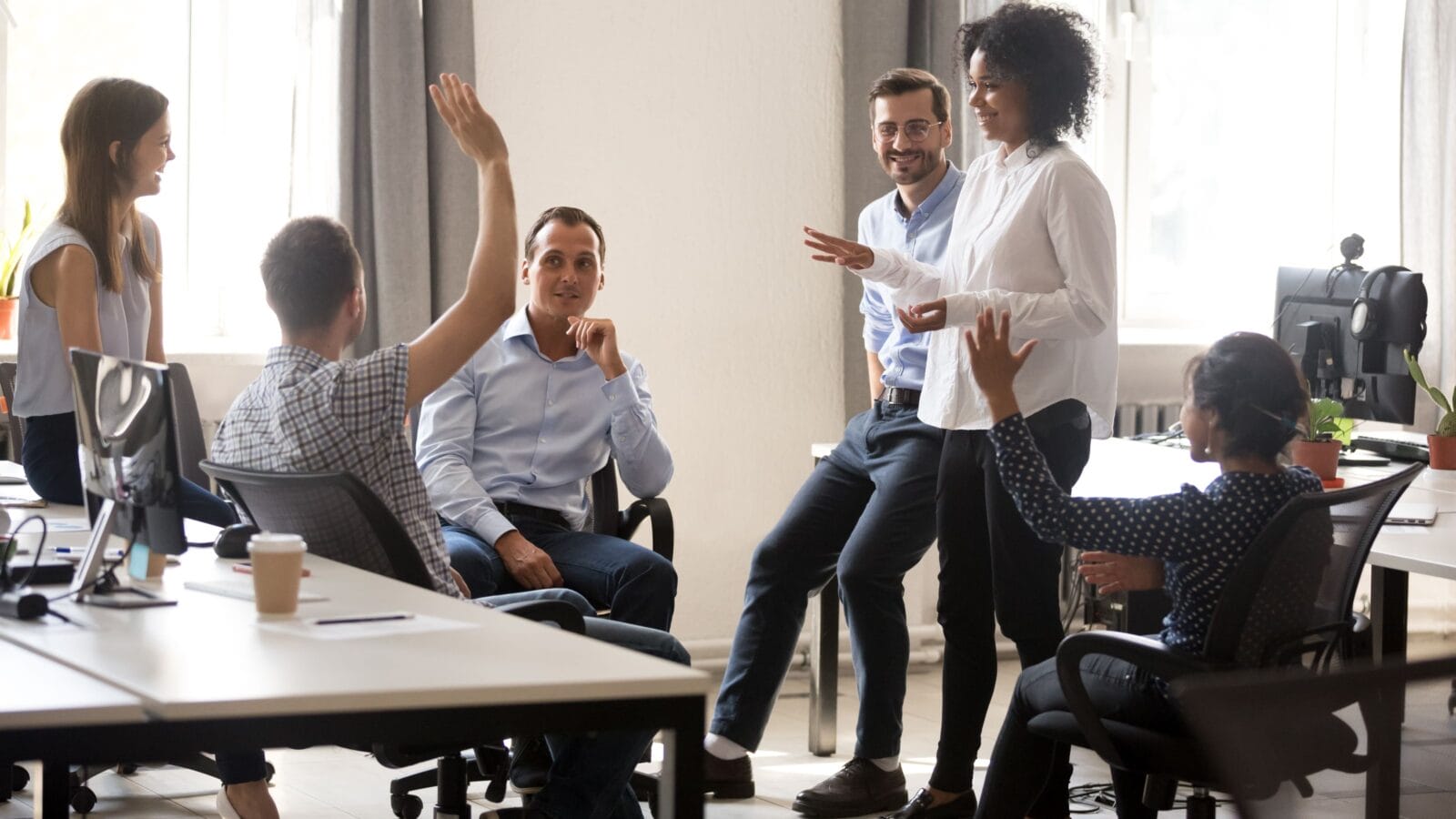 Diverse team in coworking space voting some colleagues agree raises hands