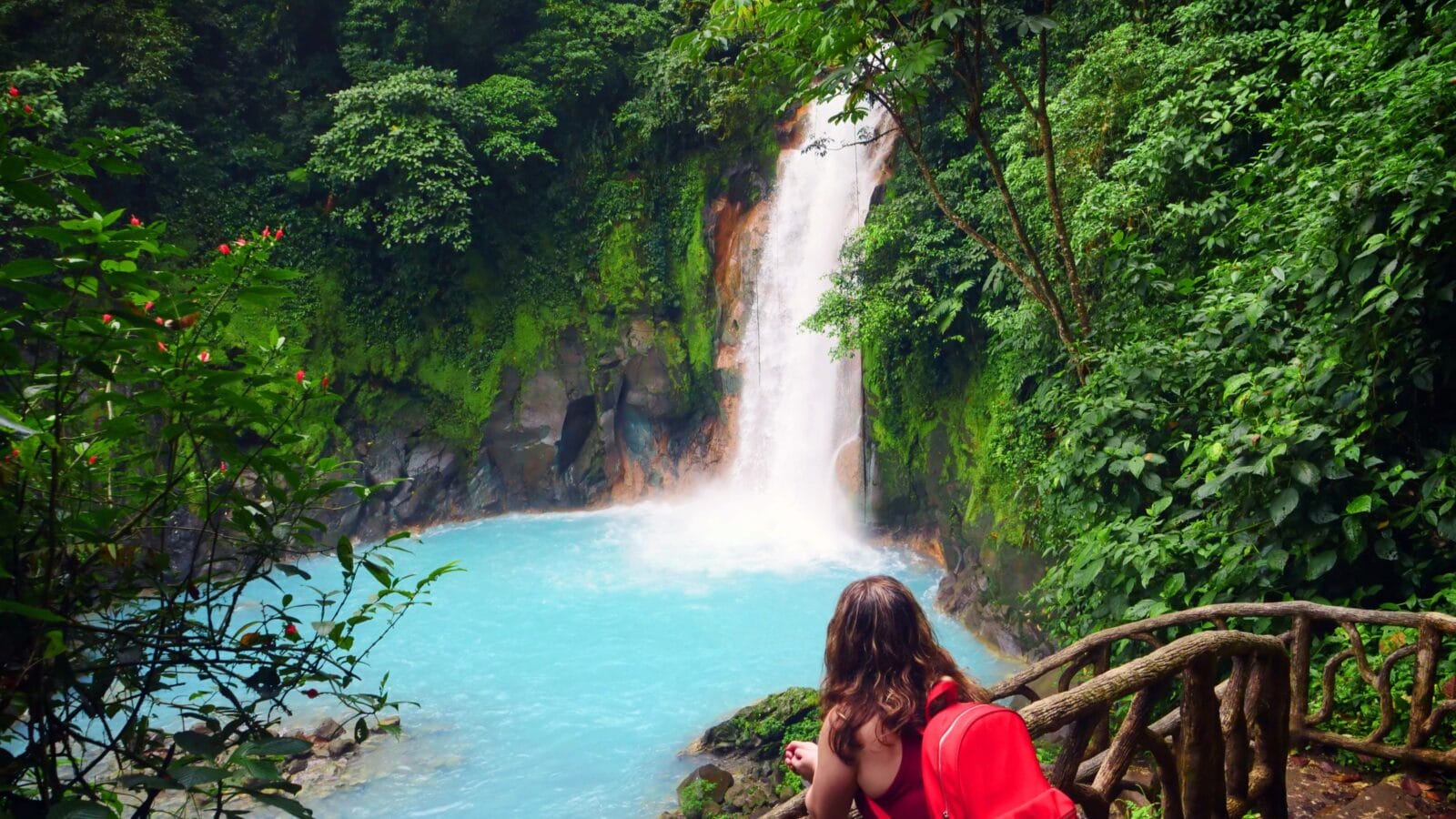 Young woman looks out over a picturesque rain forest waterfall in Costa Rica