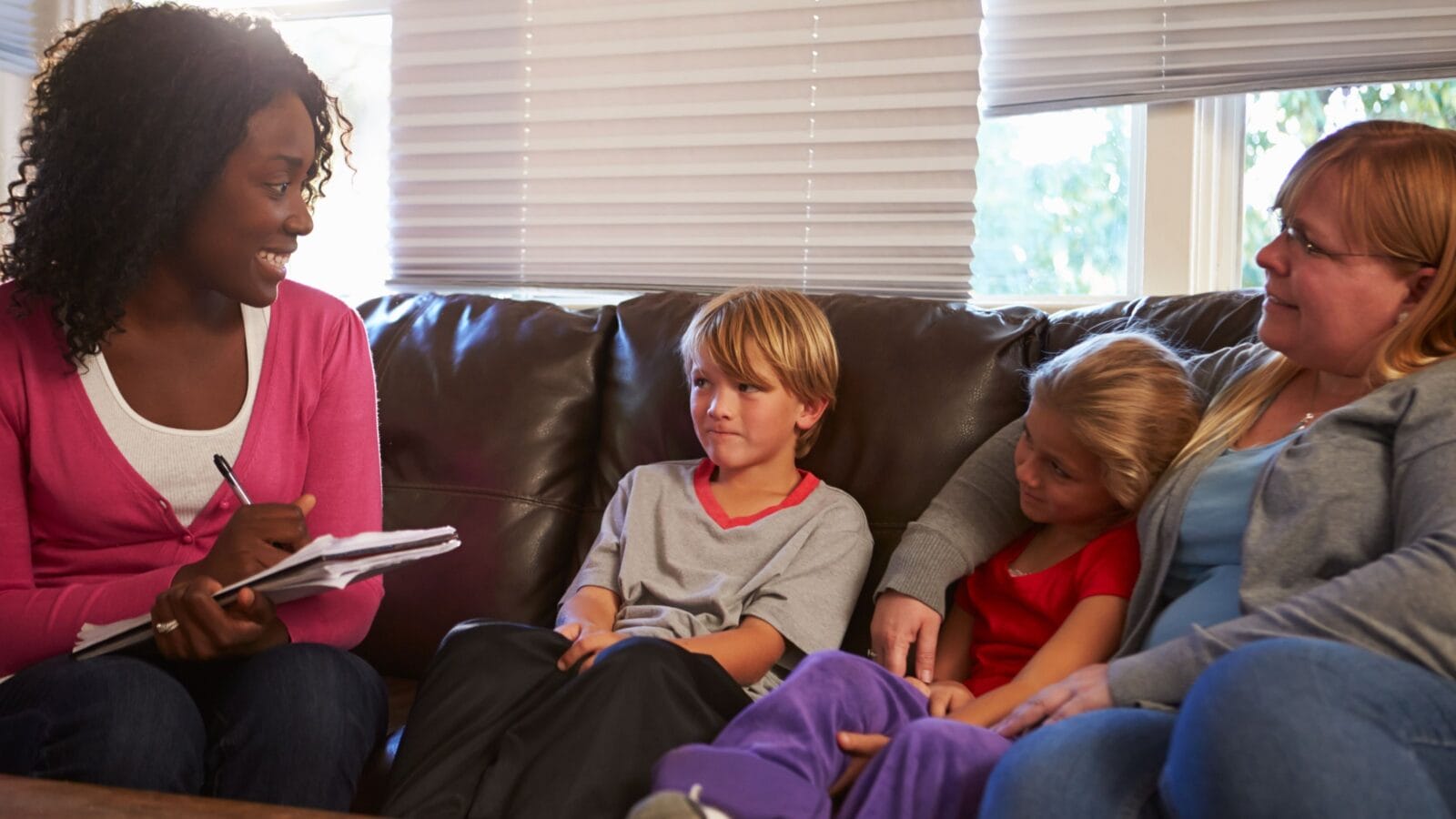 Social Worker Talking To Mother And Children At Home