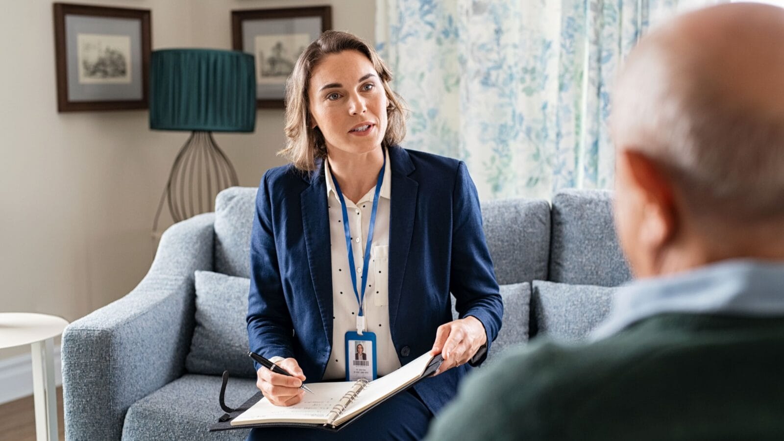 Mature social worker talking to senior man and taking notes of health progress