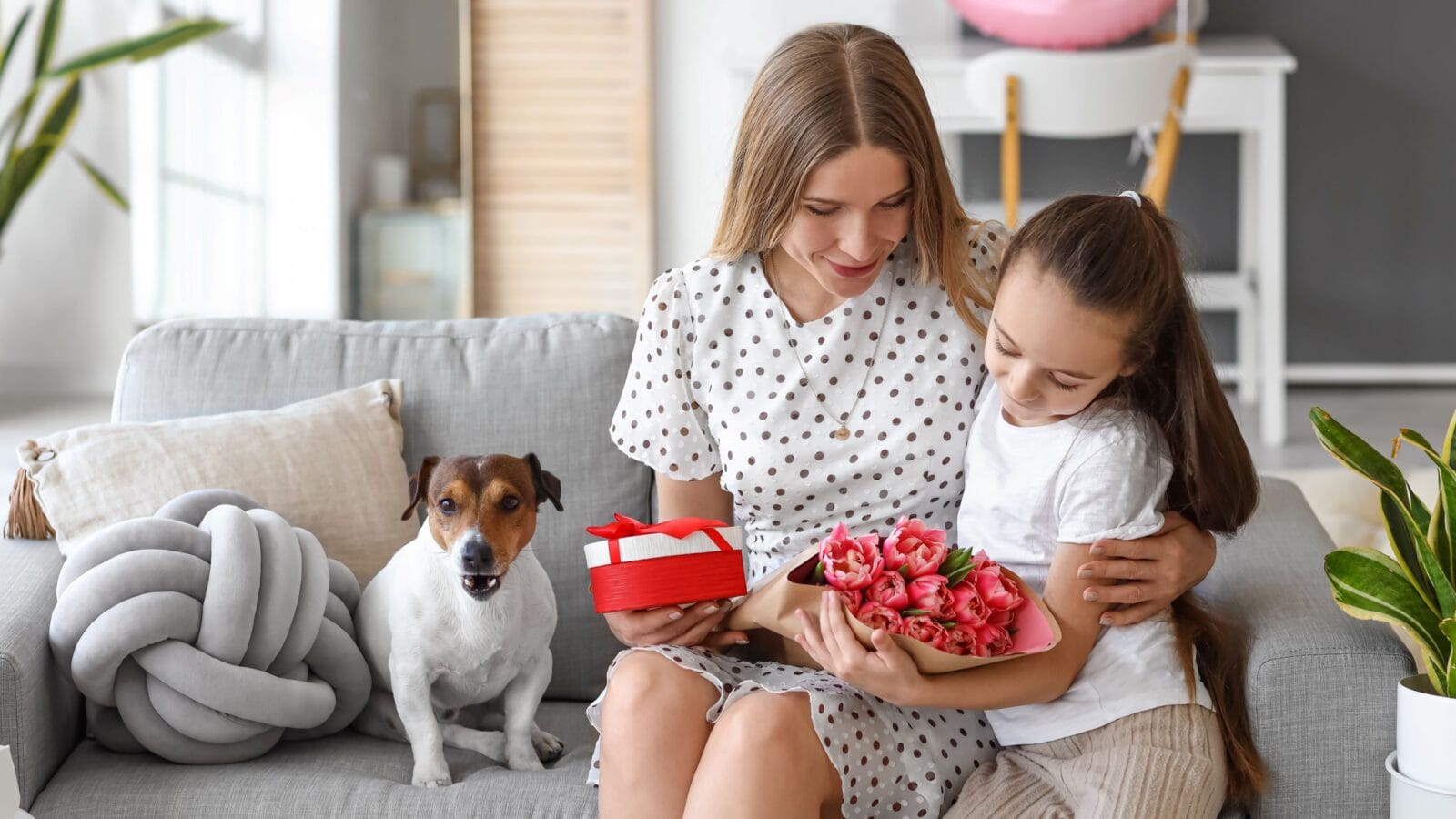 Little girl with her mother, gifts and cute dog at home on International Women's Day