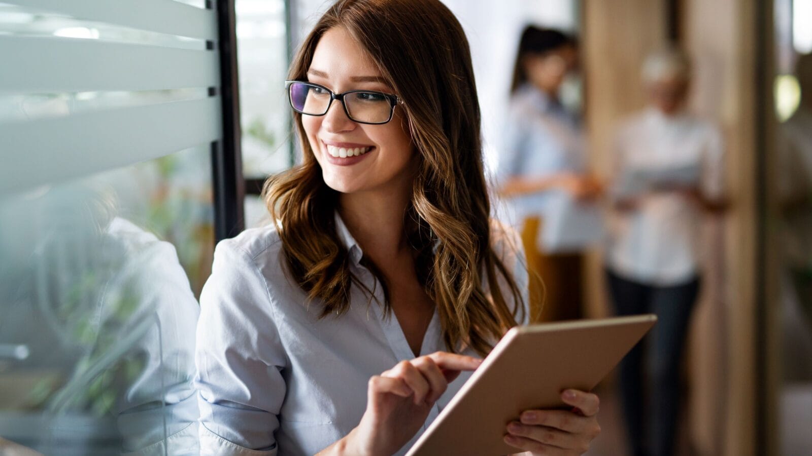 Young happy business woman working with tablet in corporate office