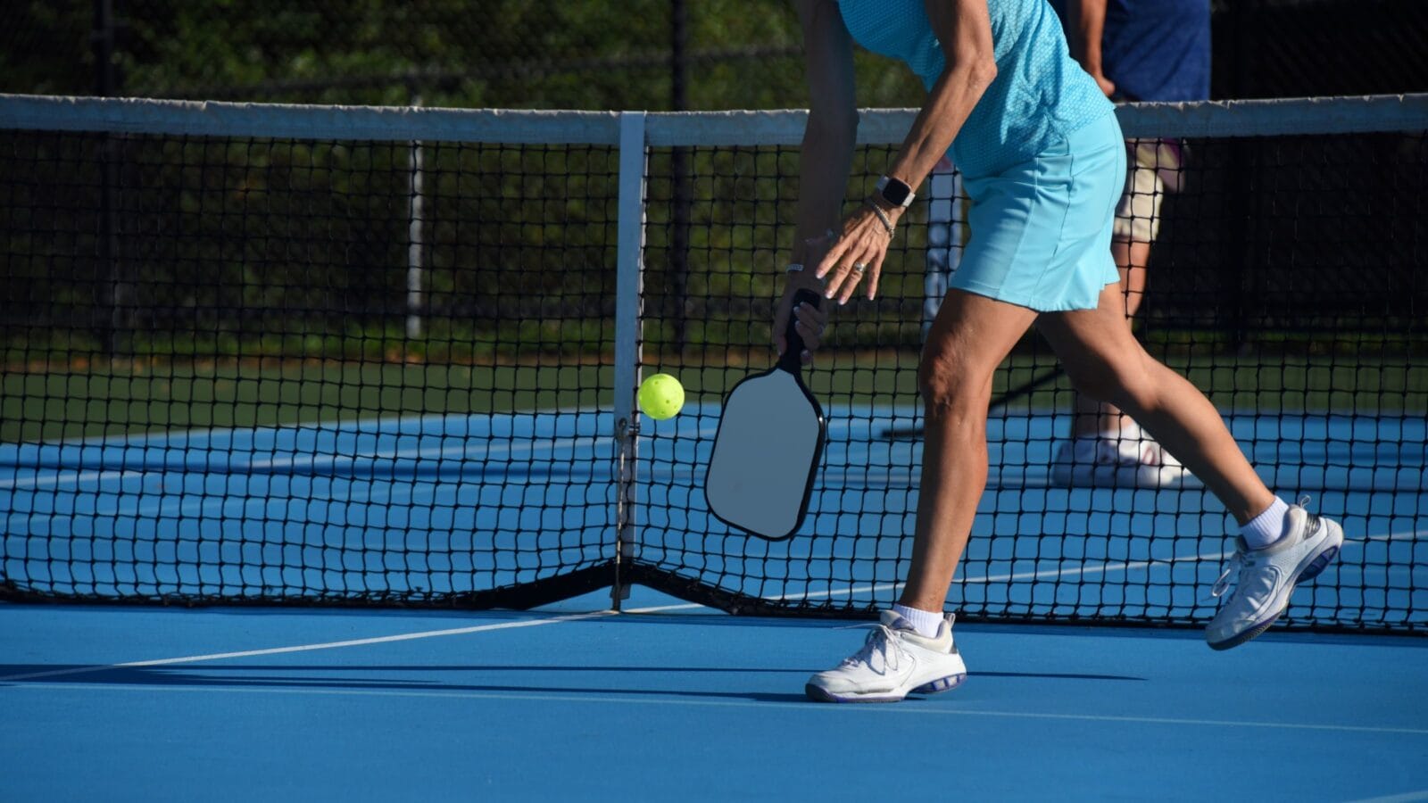 Senior female leans down to serve the ball during a pickle ball match in Asheville, North Carolina