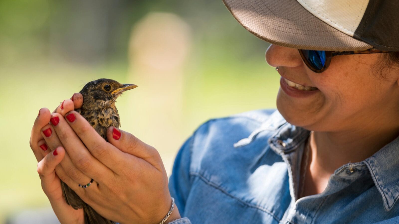 Woman talking to a baby bird retrieved from the floor.