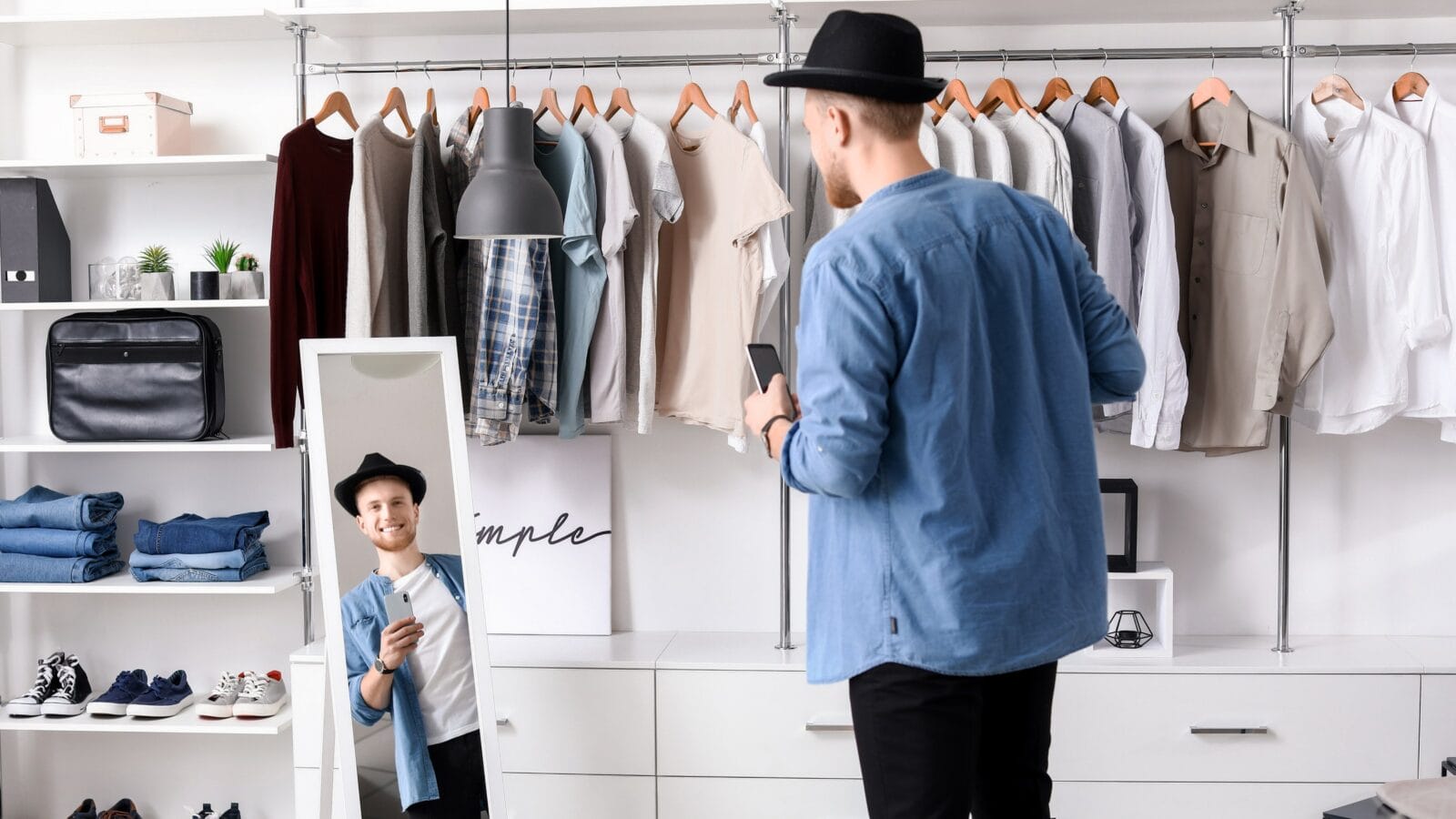 Handsome man trying on stylish clothes in dressing room