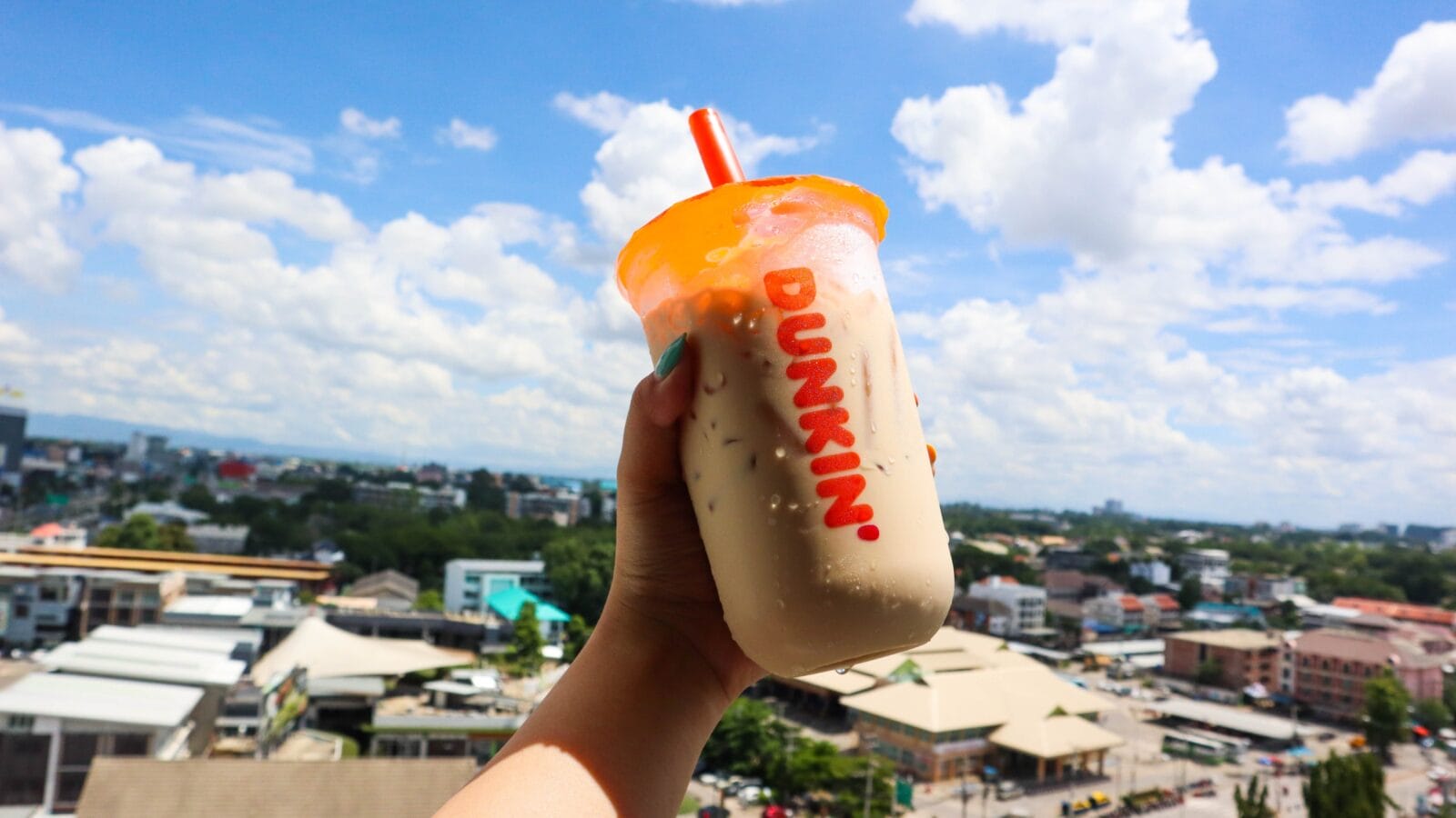 Girl holding glass of iced coffee of Dunkin Donuts shop