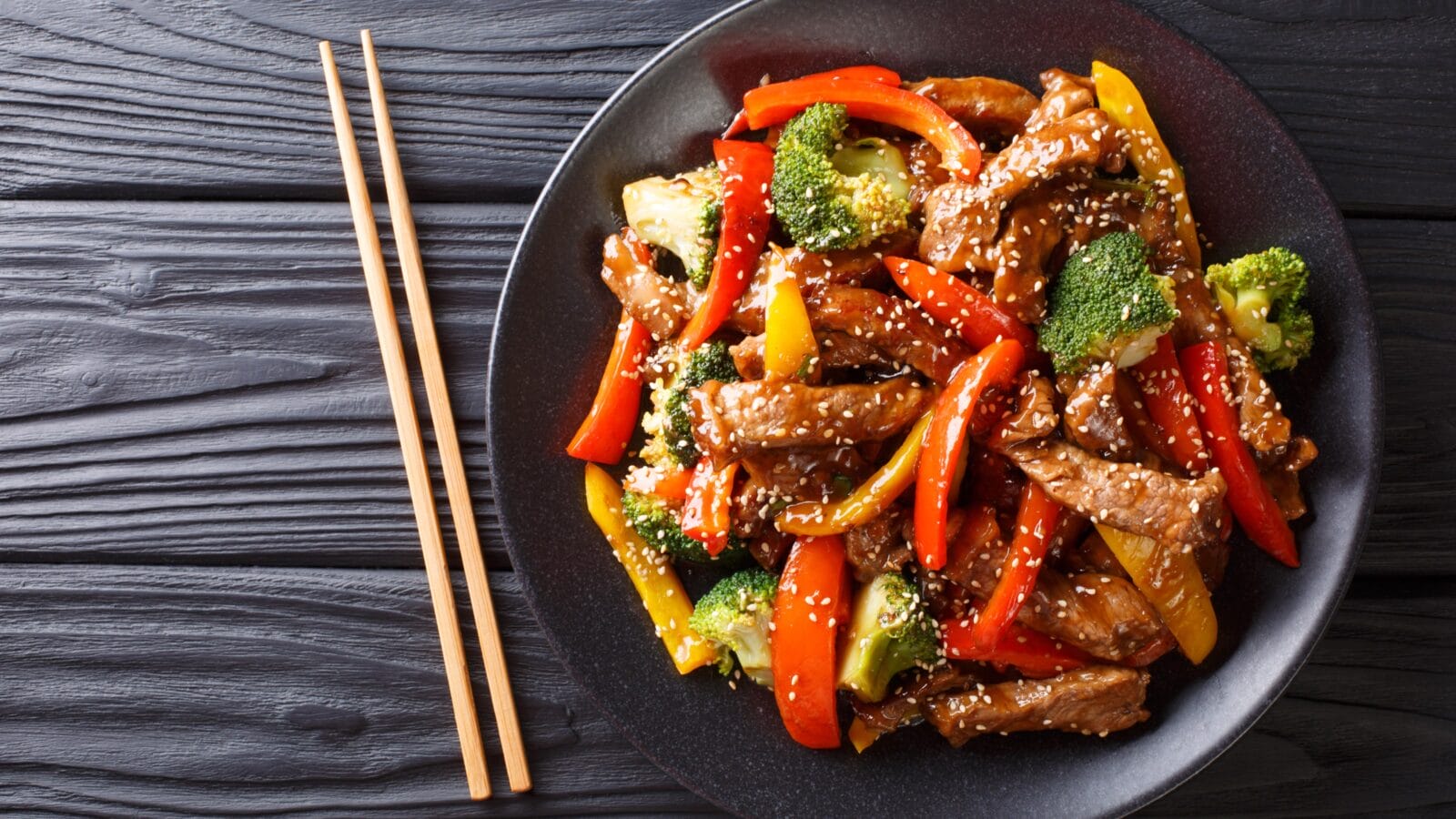 delicious Asian teriyaki beef with red and yellow bell peppers, broccoli and sesame seeds