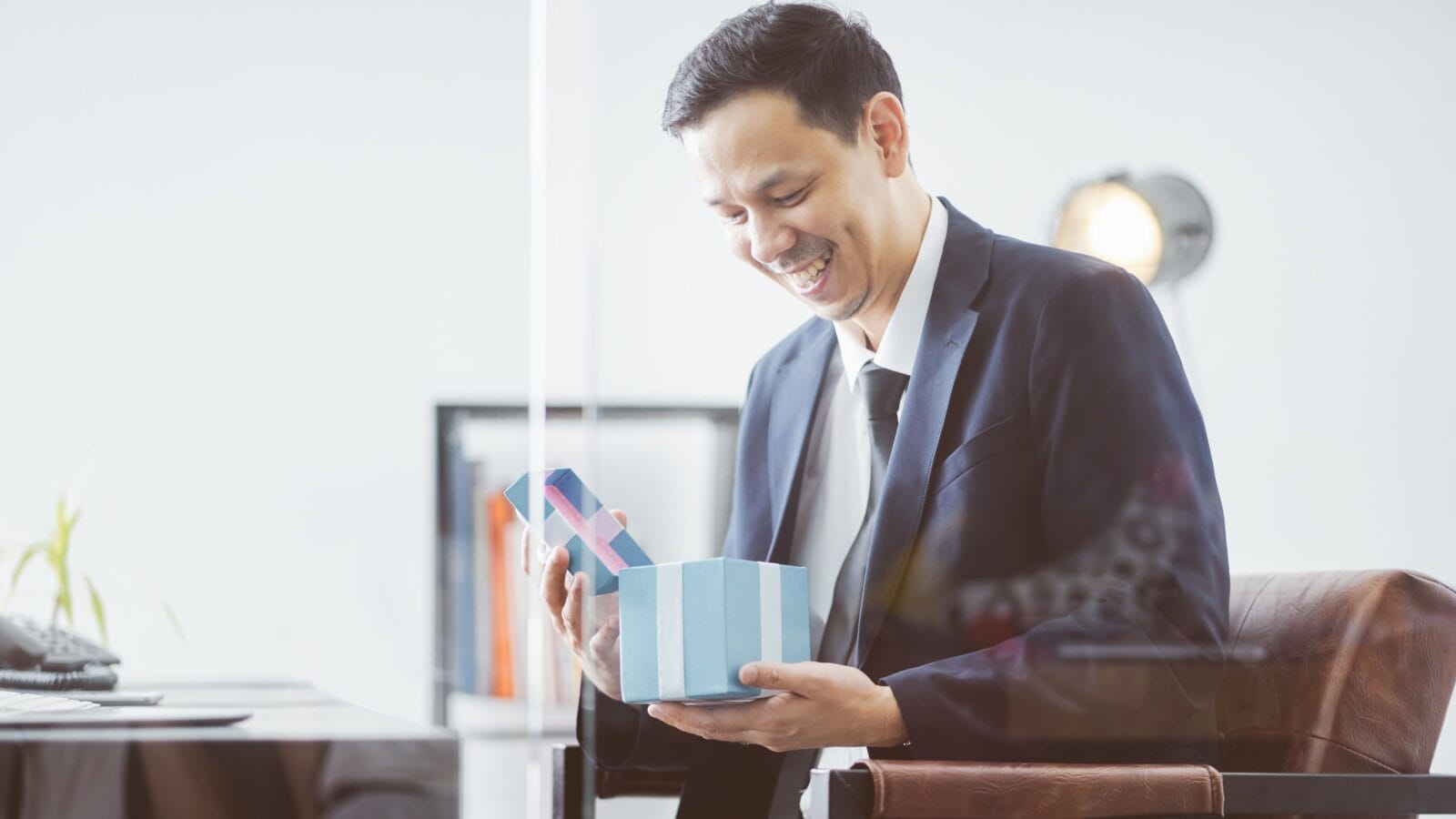 Asian Businessman happy smile open gift box.