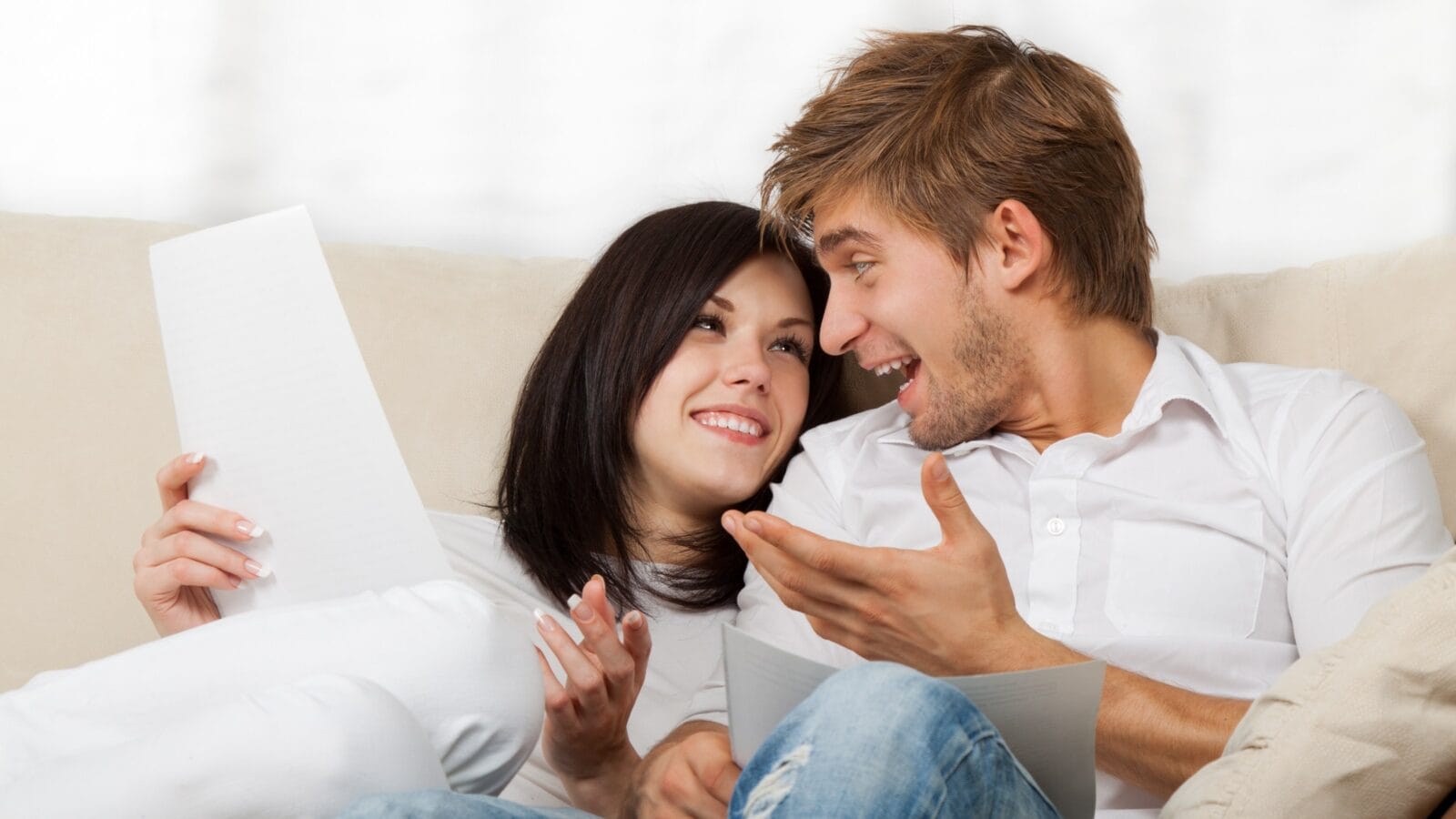 Happy couple reading a letter in their living room