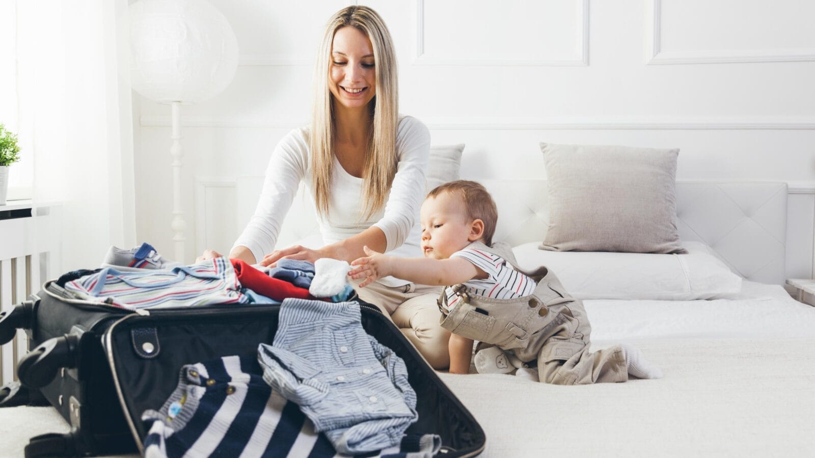 Happy mother with her child packing clothes for their holiday