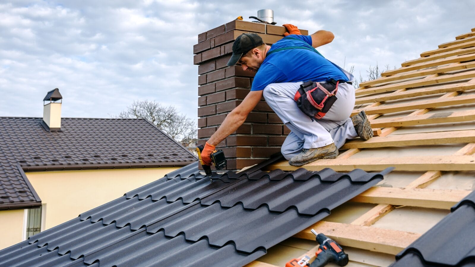 a professional master (roofer) with electric screwdriver covers repairs the roof