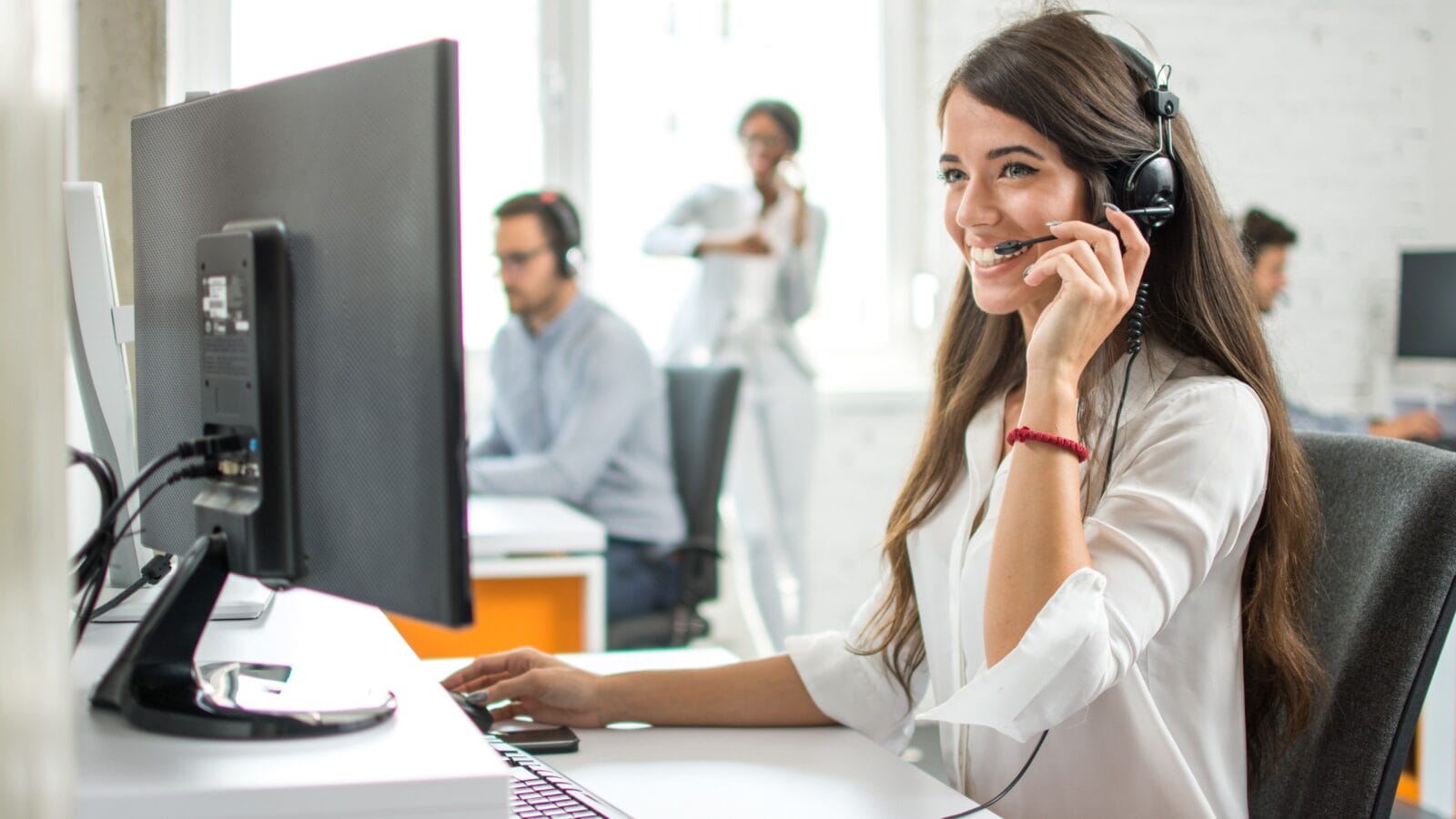 Happy smiling female customer service operator working on computer in office