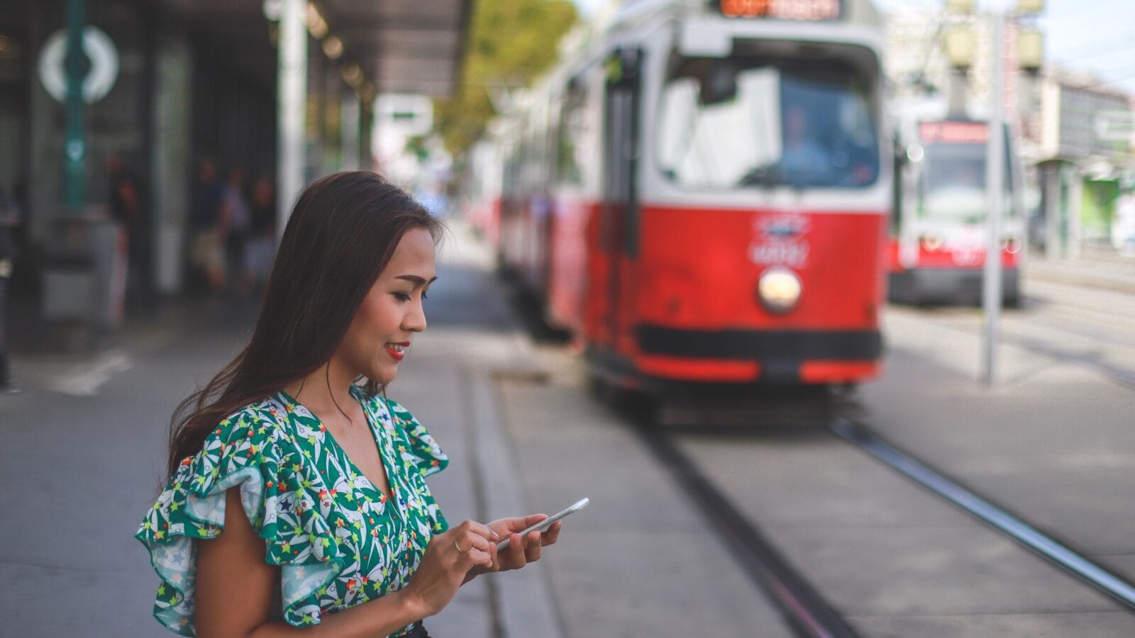 Young woman using smartphone while waiting for tram.