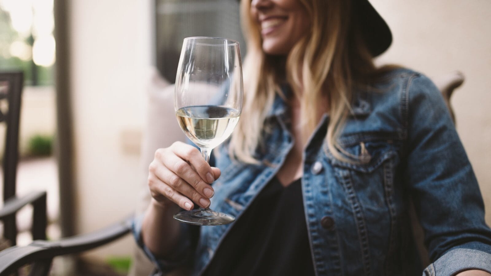 Happy blonde woman enjoying white wine and smiling